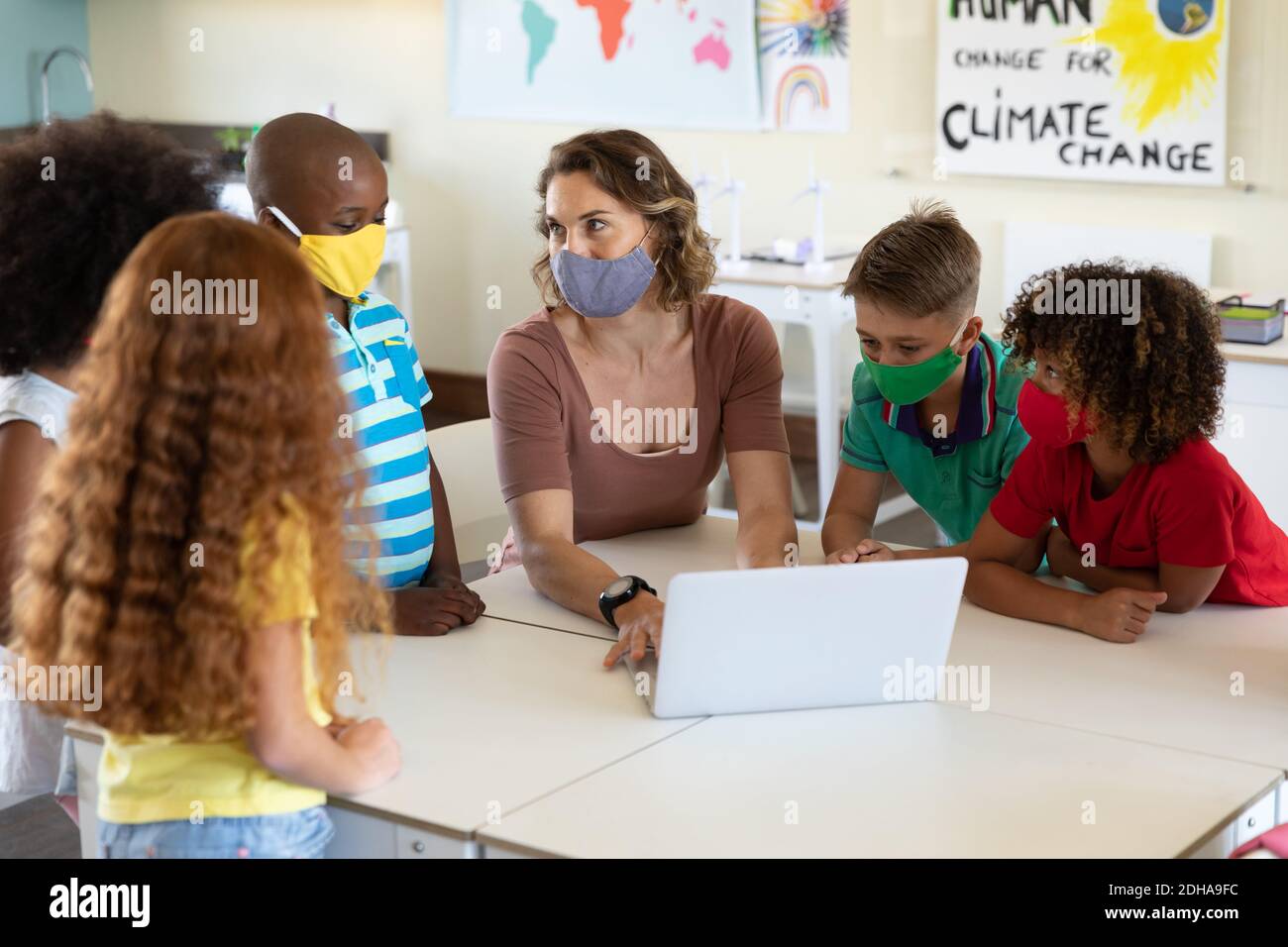 Weibliche Lehrerin trägt Gesichtsmaske mit Laptop, um Schüler zu lehren In der Klasse Stockfoto