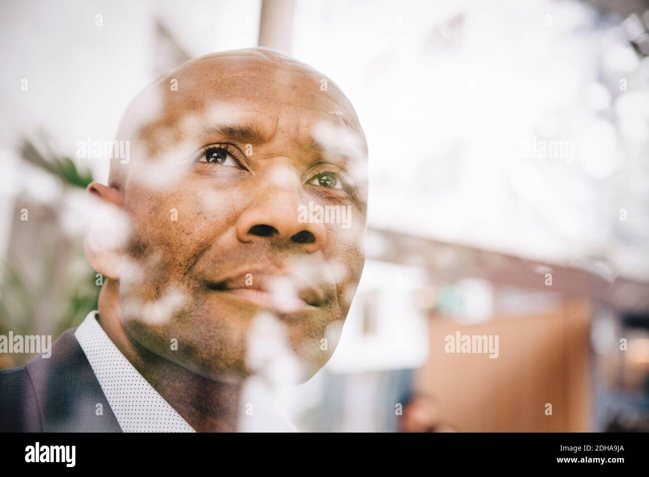 Betrachten reifen Unternehmer Blick weg durch Glasfenster gesehen Stockfoto