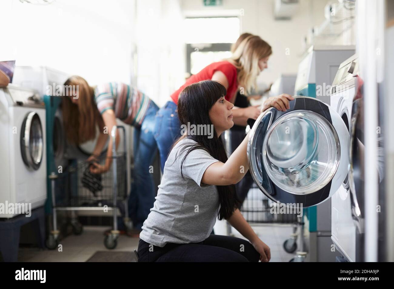 Studentinnen, die die Waschmaschine im Waschsalon benutzen Stockfoto