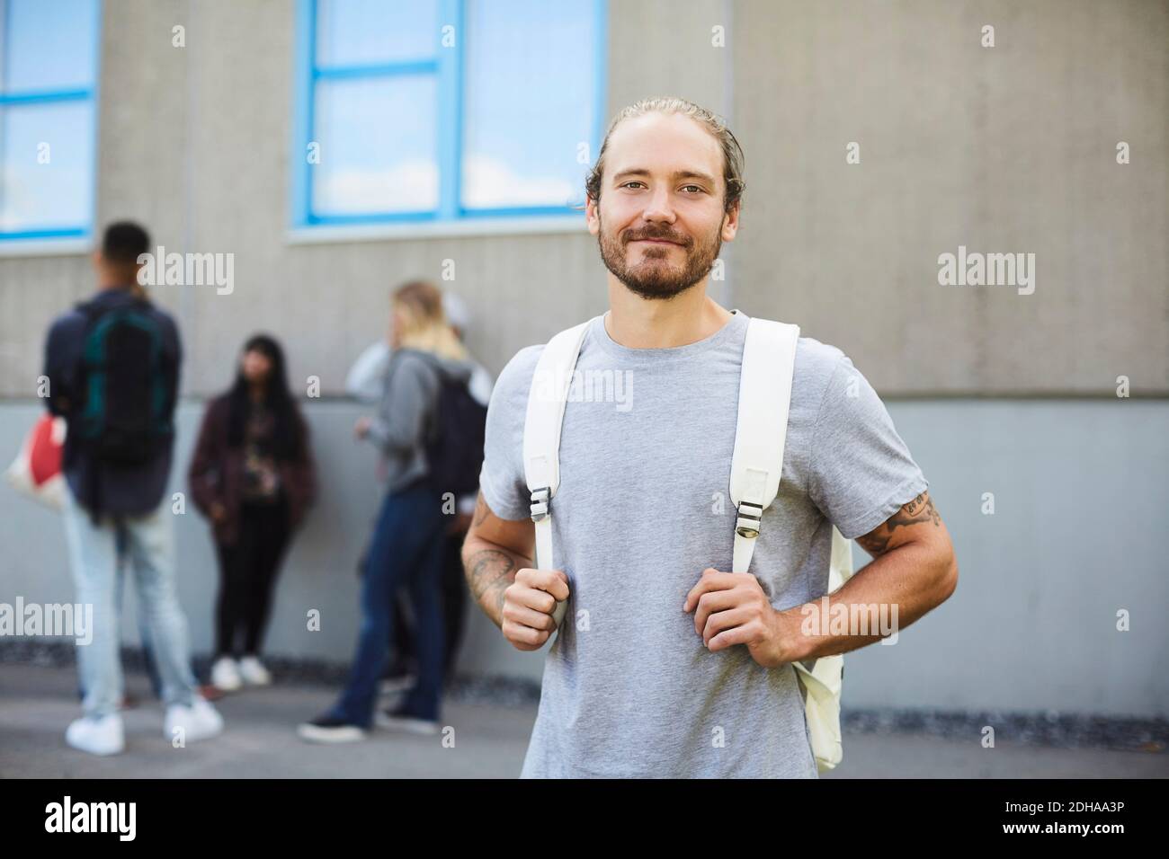 Porträt eines lächelnden Studenten auf dem Campus mit Freunden stehen Im Hintergrund Stockfoto