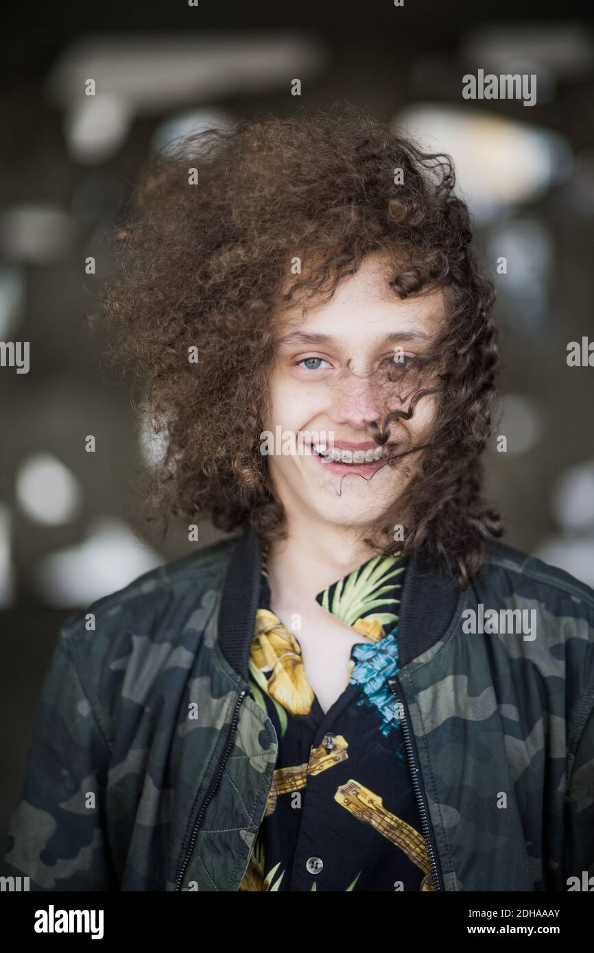 Portrait von lächelndem Teenager mit lockigen braunen Haaren an Parkhaus Stockfoto