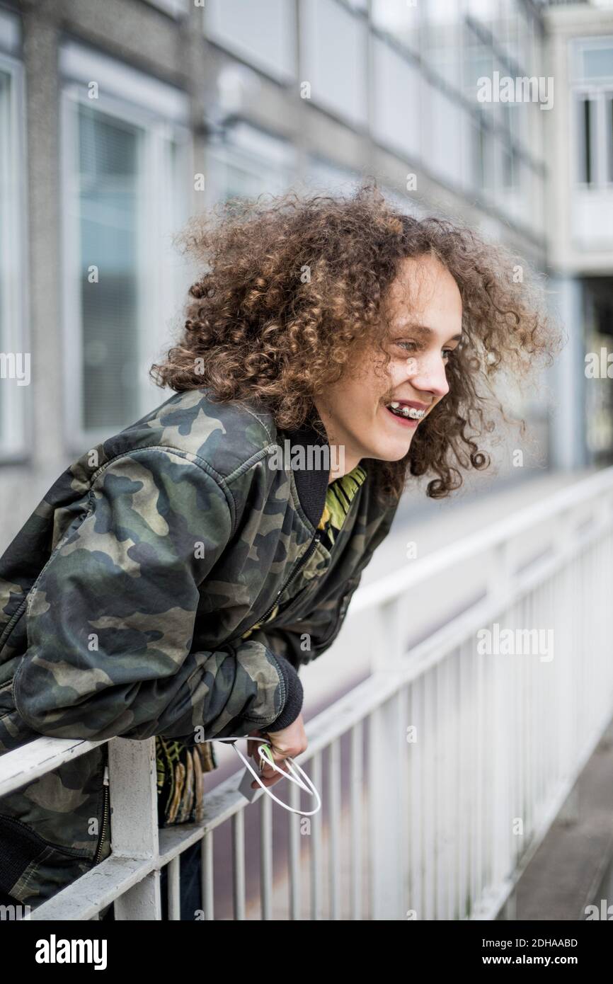 Lächelnder Teenager, der sich in der Stadt an Geländer lehnt Stockfoto