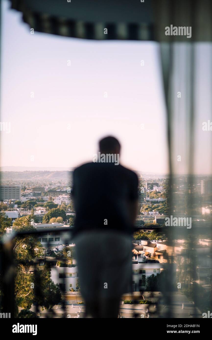 Rückansicht eines älteren Mannes, der auf dem Balkongeländer gelehnt war Stadt Stockfoto