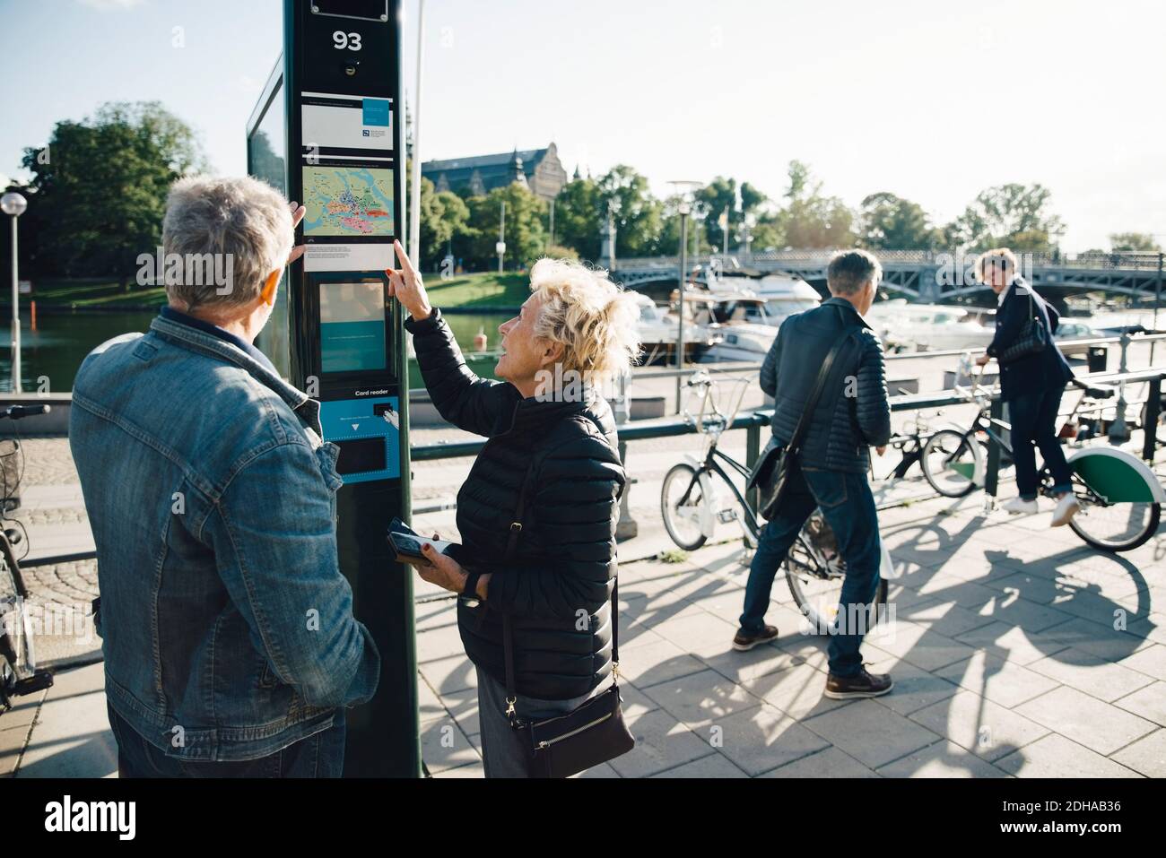Ältere Paare, die einen Fahrradautomaten auf dem Bürgersteig in der Stadt betreiben Stockfoto