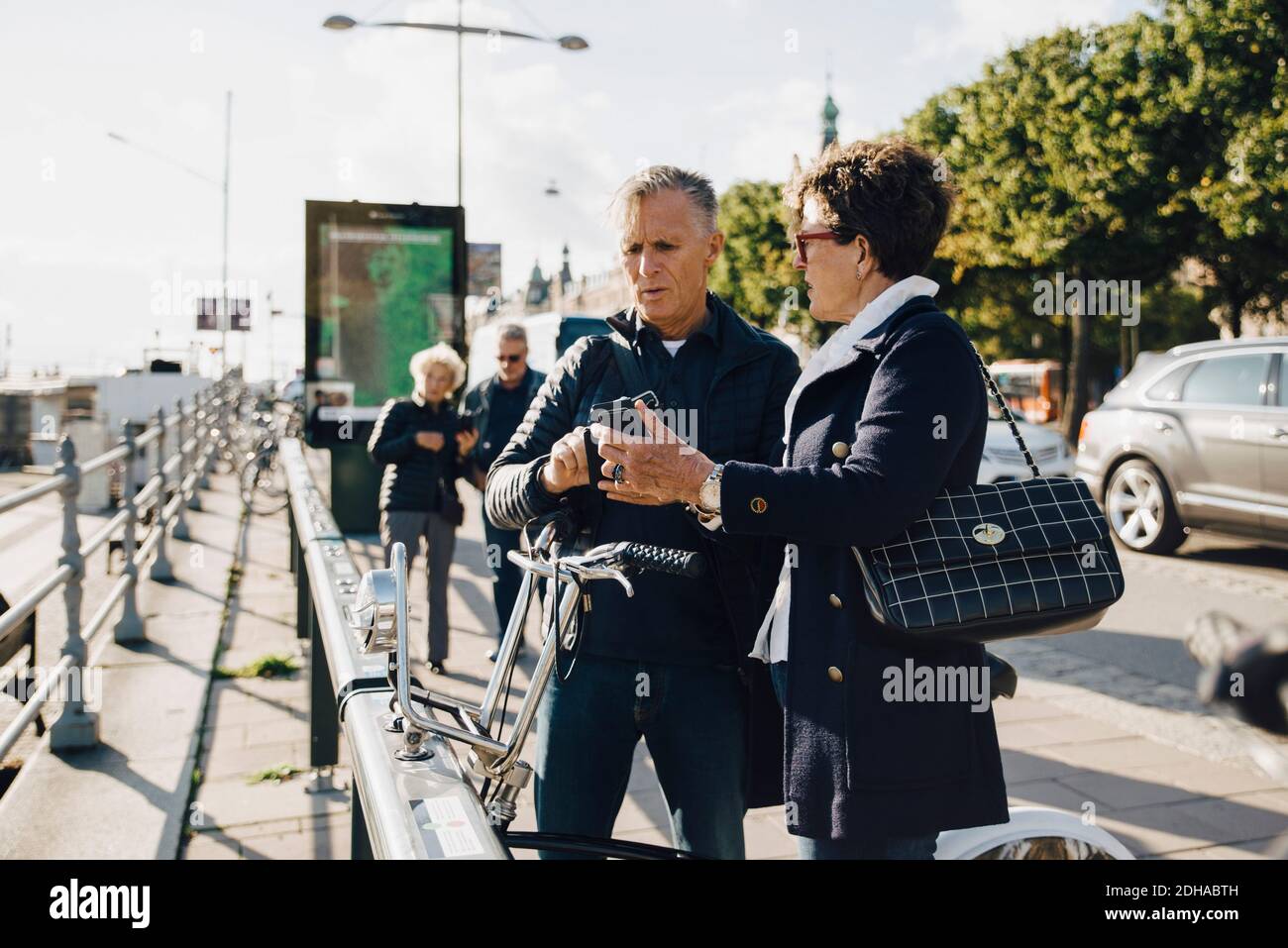 Ein älteres Paar, das auf dem Bürgersteig stand, mit dem Handy telefoniert Stadt Stockfoto