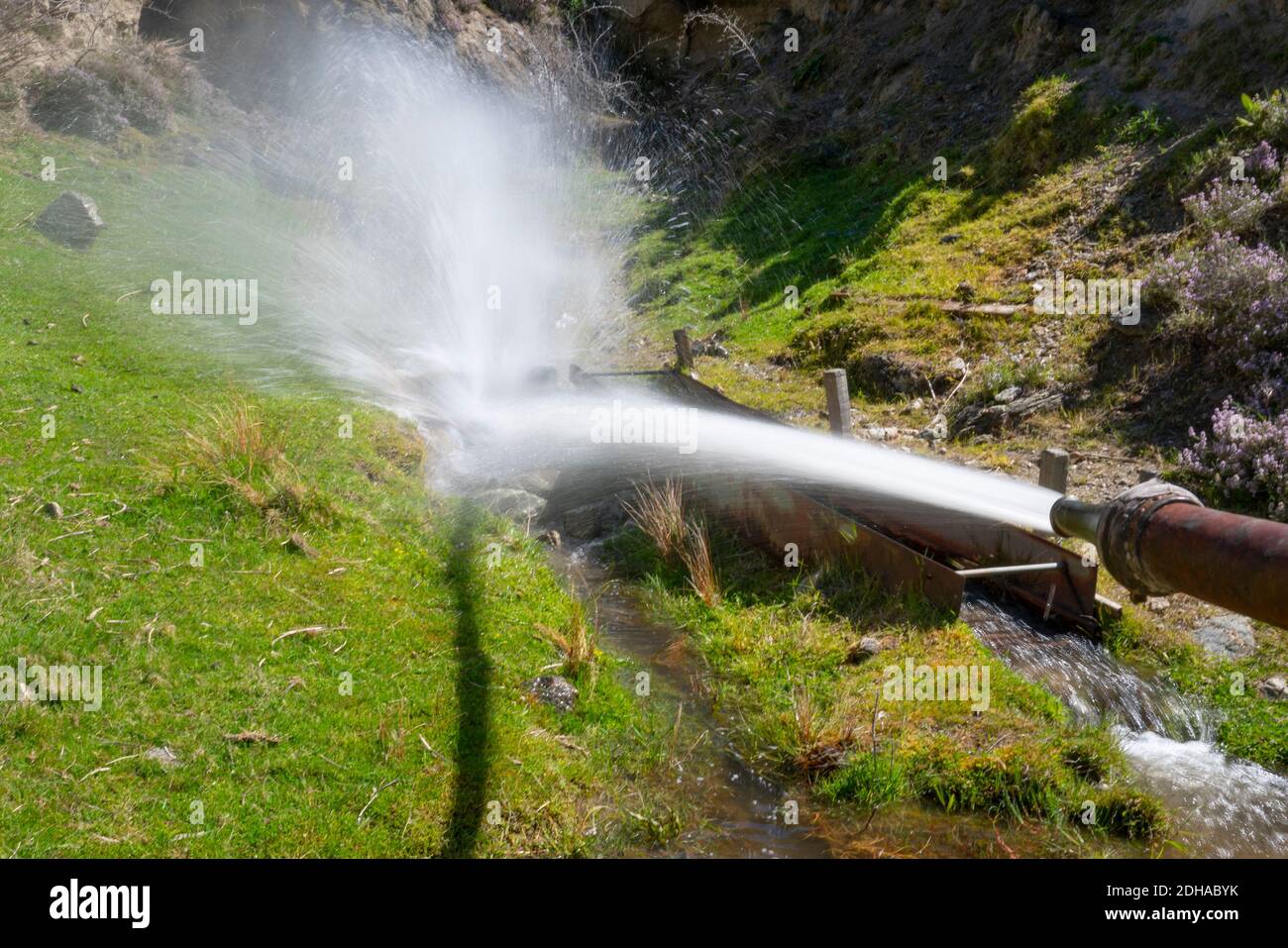 Cromwell Neuseeland - November 10 2020; Wasserstrahl zum Schleusen unter alter Hütte am Hang am Standort des alten historischen Goldgräberdorfes in Kawarau G Stockfoto