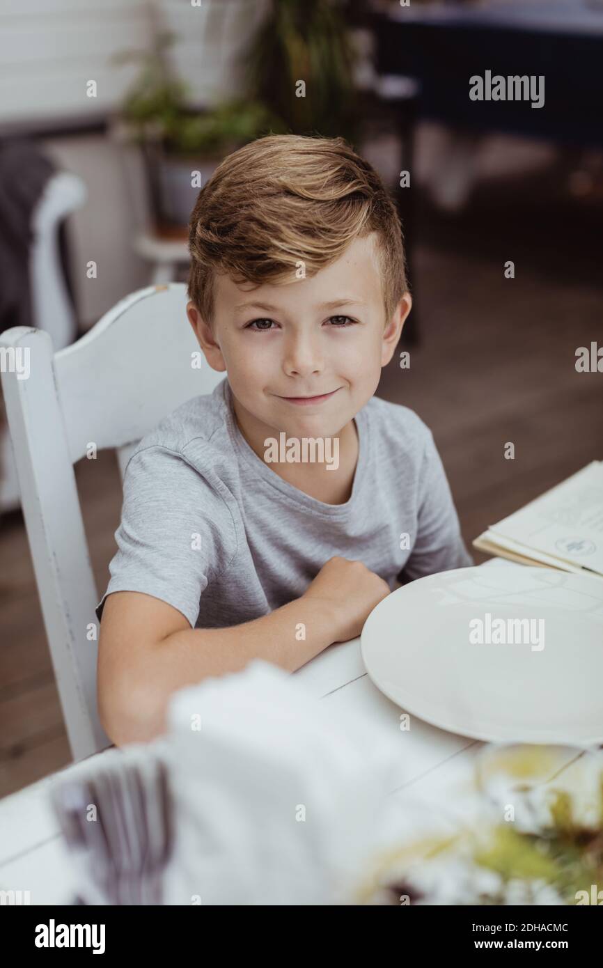 Porträt eines lächelnden Jungen, der am Tisch im Restaurant sitzt Stockfoto