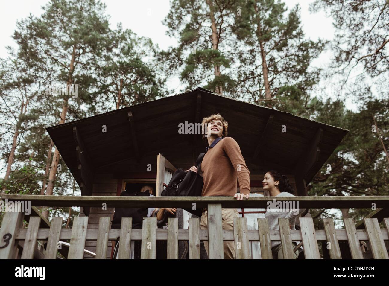 Man hatte einen niedrigen Blick auf lächelnde Freunde, die auf der Veranda standen Haus Stockfoto