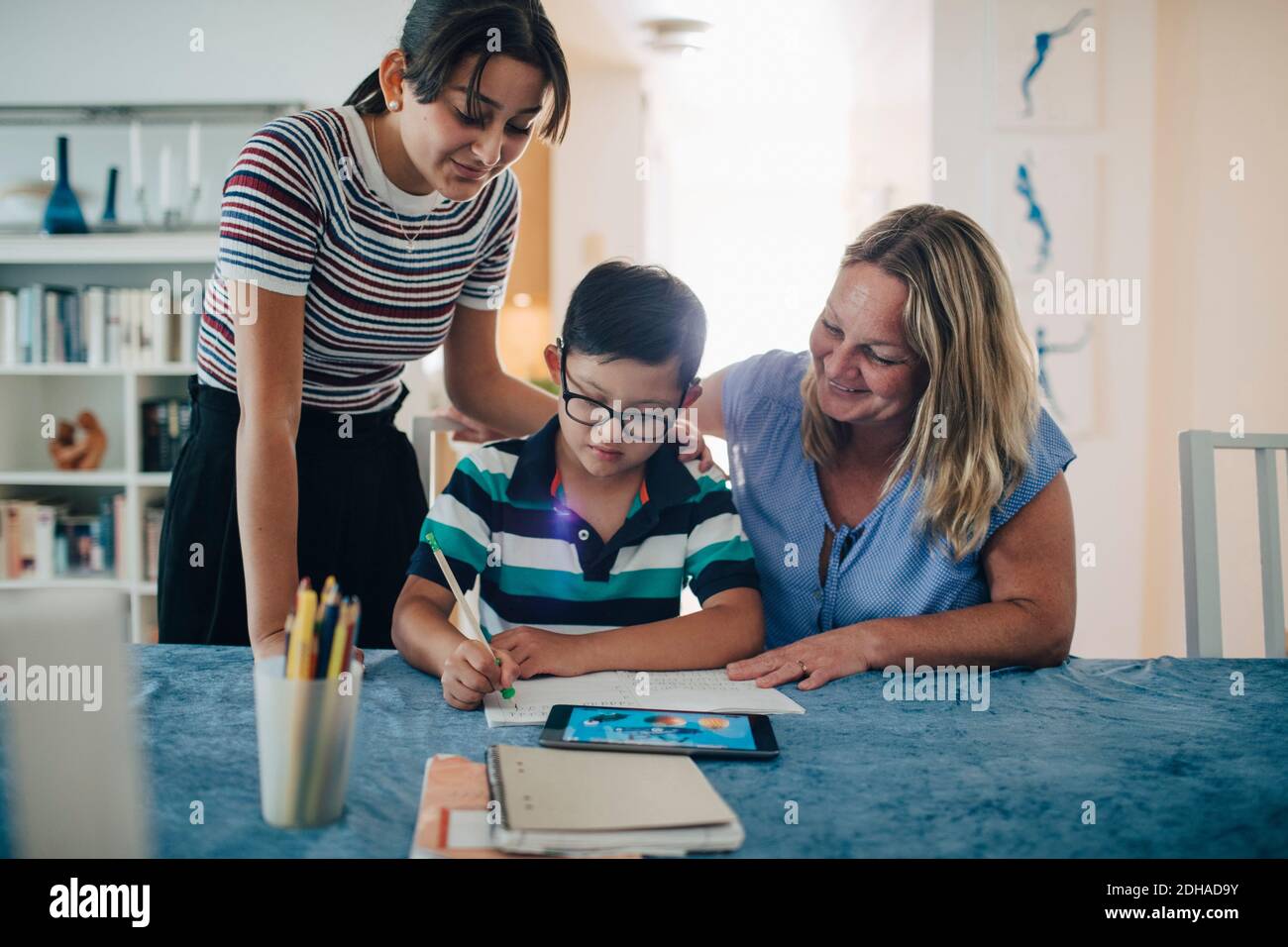 Lächelnde Mutter mit Teenagermädchen, die Jungen beim Studieren ansieht Tabelle Stockfoto