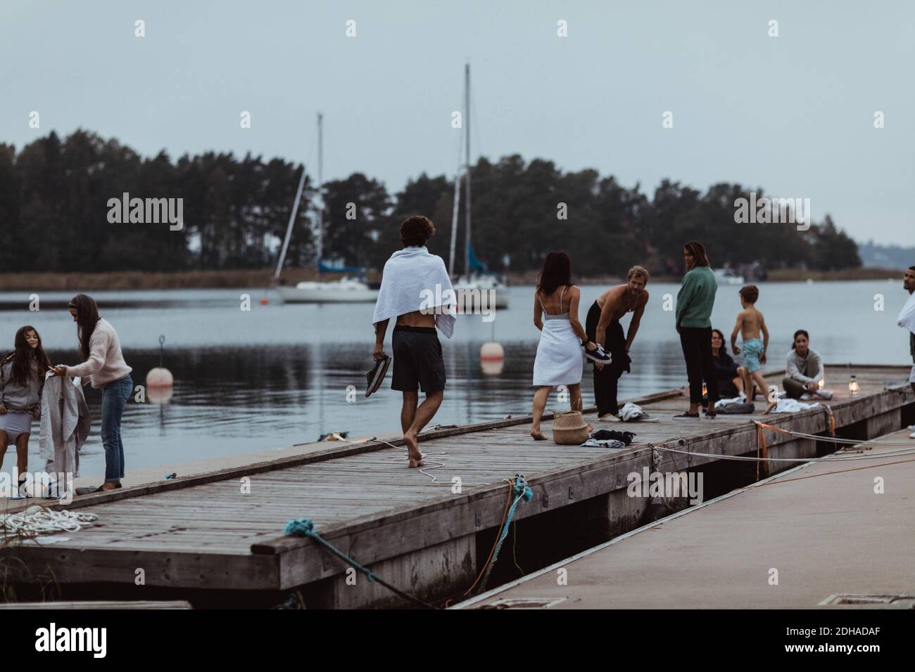 Gemischte Altersgruppe von Leuten, die Urlaub am Pier genießen Meer gegen Himmel Stockfoto