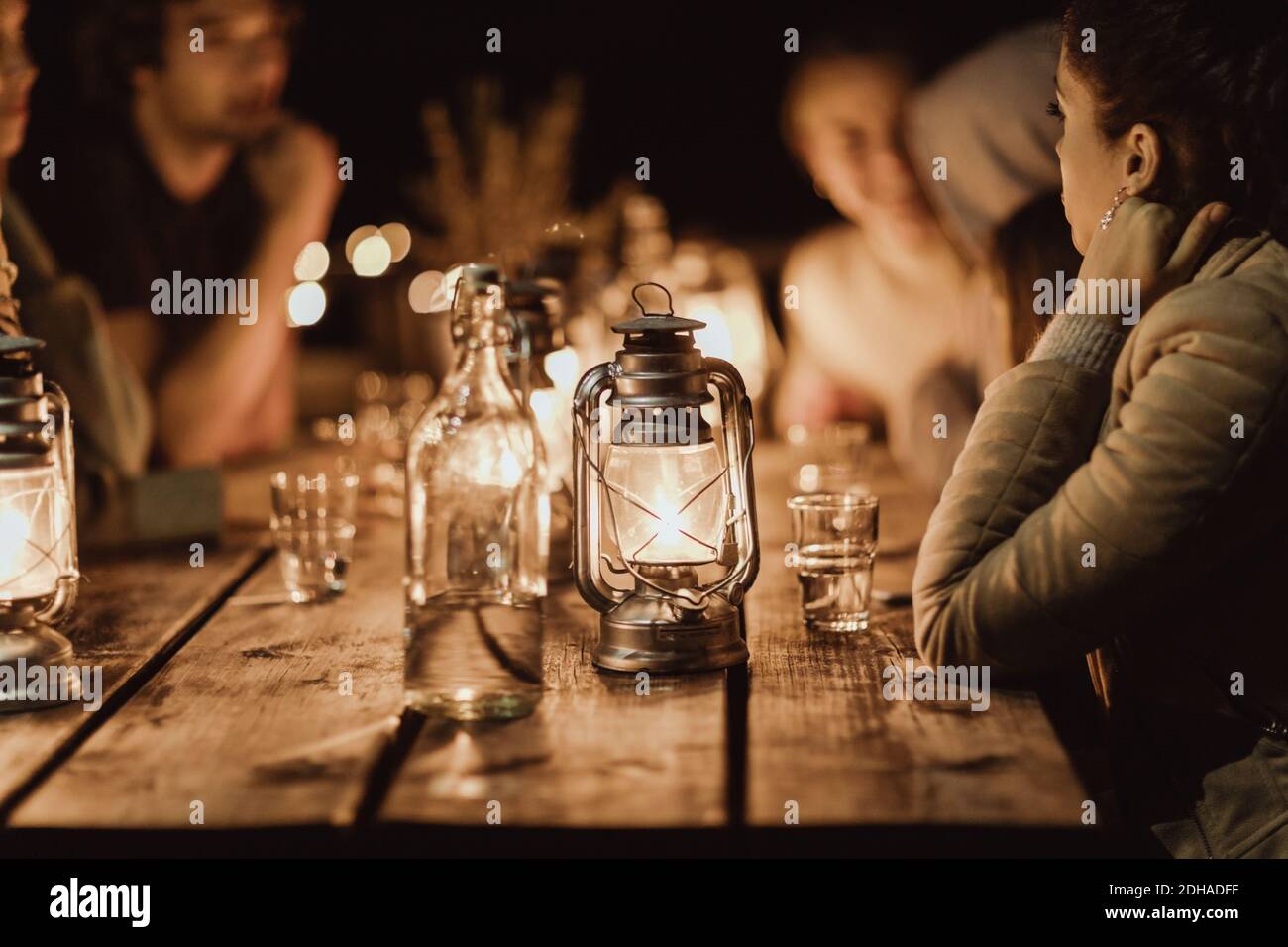 Abends sitzen Menschen um einen beleuchteten Tisch im Restaurant herum Stockfoto