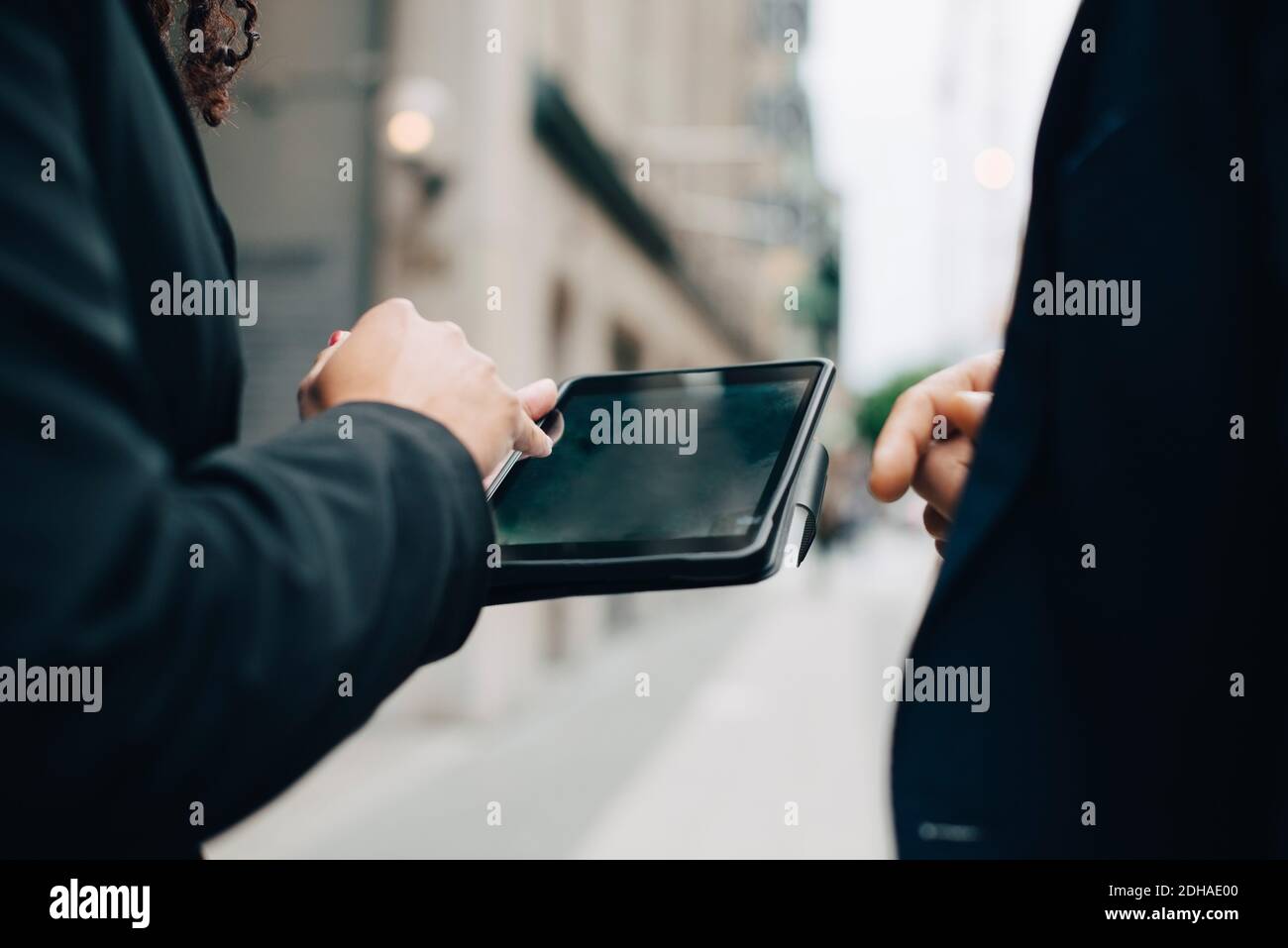 Mittelteil von Geschäftskollegen mit digitalem Tablet, das in der Stadt steht Stockfoto