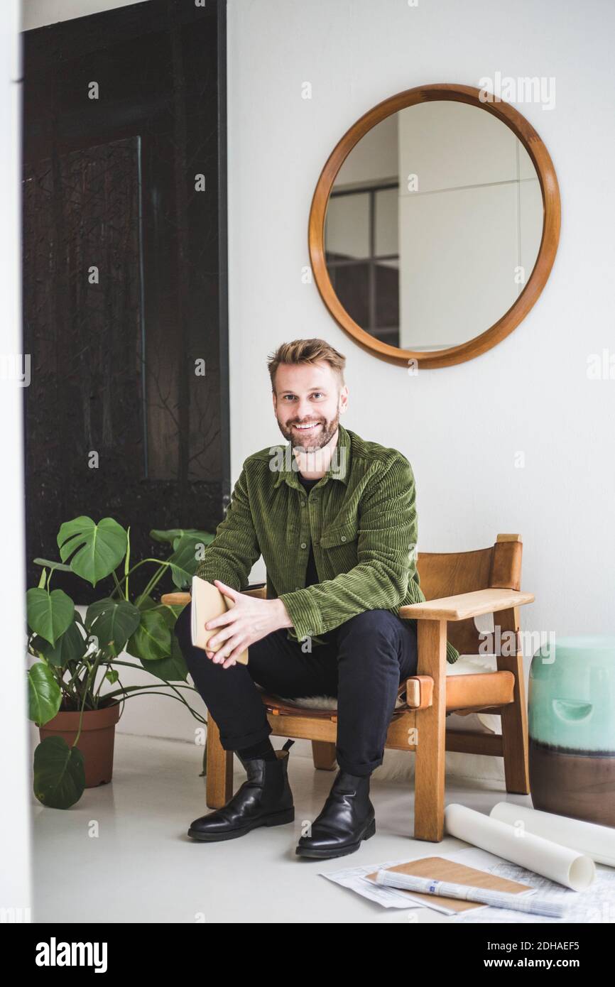 Porträt eines lächelnden männlichen Unternehmers mit Buch zu Hause sitzen Büro Stockfoto