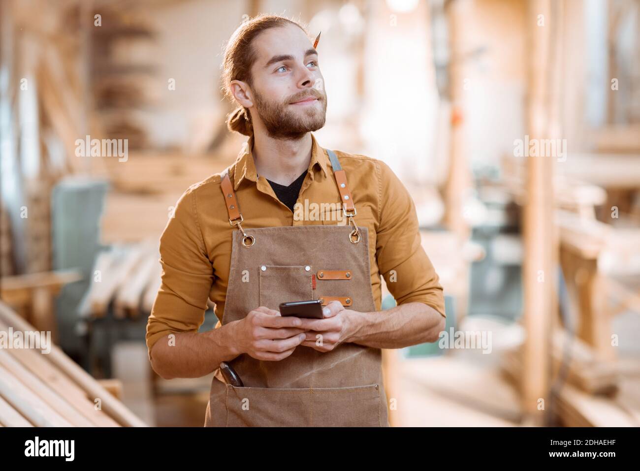 Porträt eines schönen Zimmermanns mit Smartphone, die eine Bremse während der Holzarbeiten in der Werkstatt Stockfoto