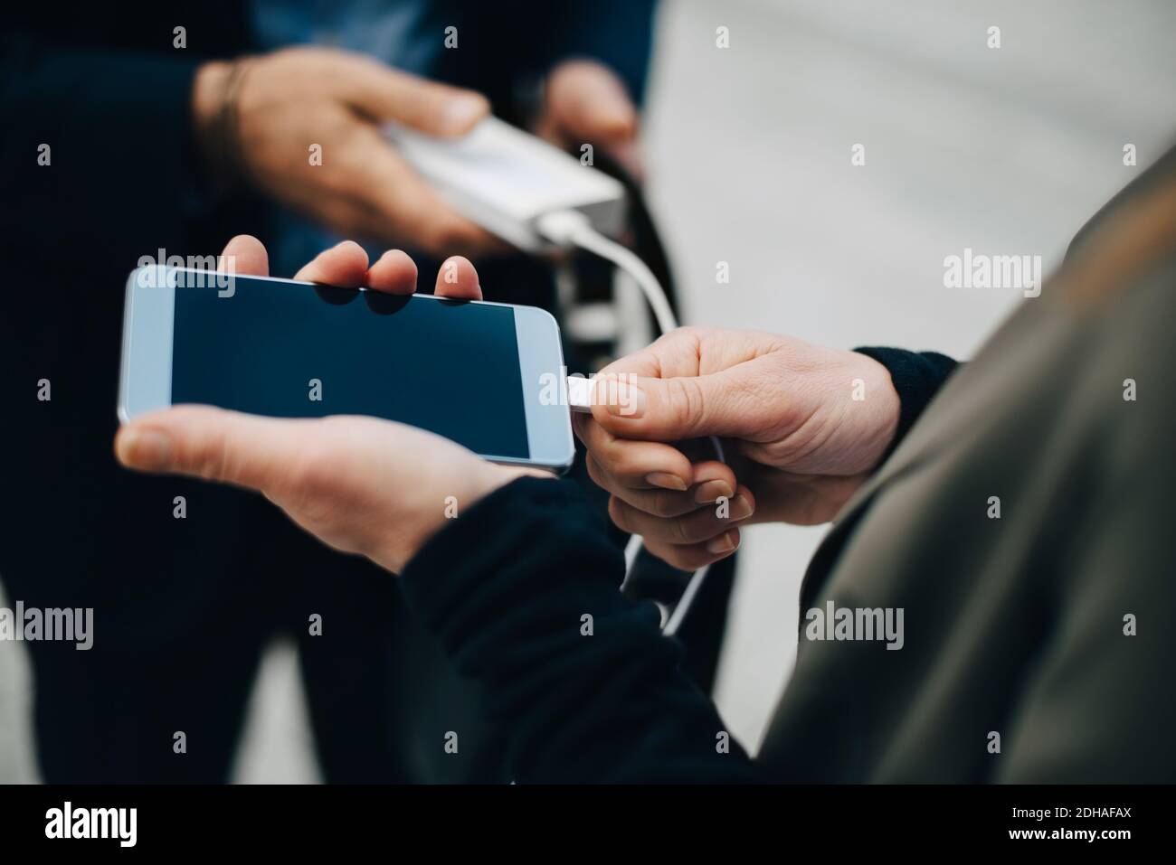 Mittelteil der reifen Geschäftsfrau Laden Handy während des Stehens mit Mitarbeiter Stockfoto