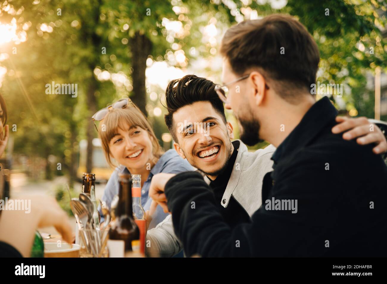 Glücklicher junger Mann, der von einem männlichen und weiblichen Freund sitzt Soziale Treffen Stockfoto