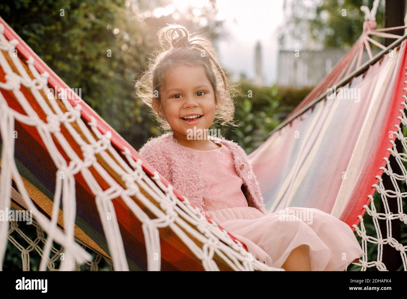 Portrait von lächelndem Mädchen, das in der Hängematte im Hinterhof sitzt Stockfoto