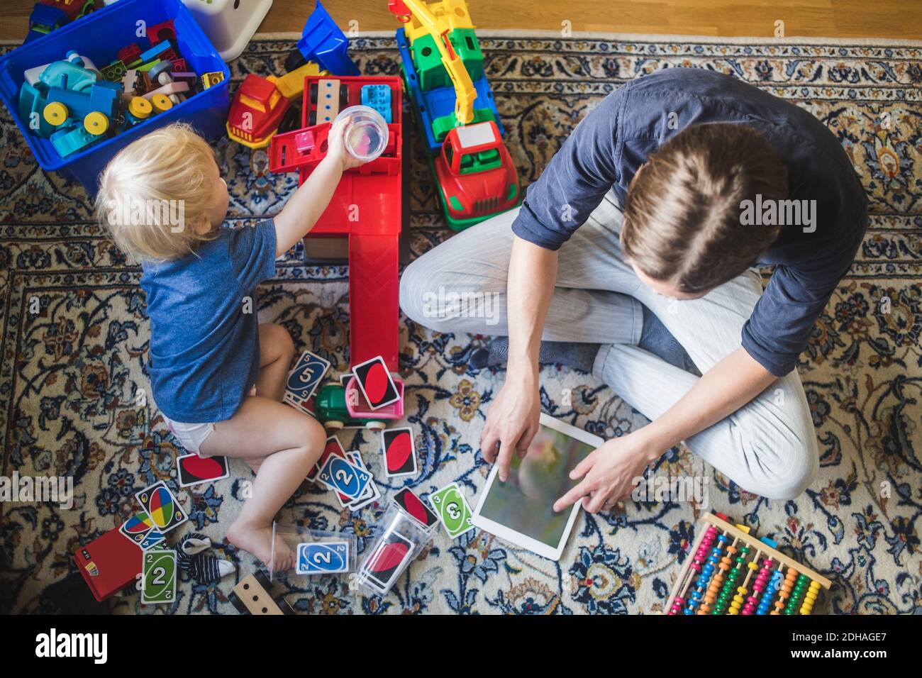 High-Winkel-Ansicht von blonden Baby Junge spielen Spielzeug durch Vater mit digitalen Tablet im Wohnzimmer zu Hause Stockfoto