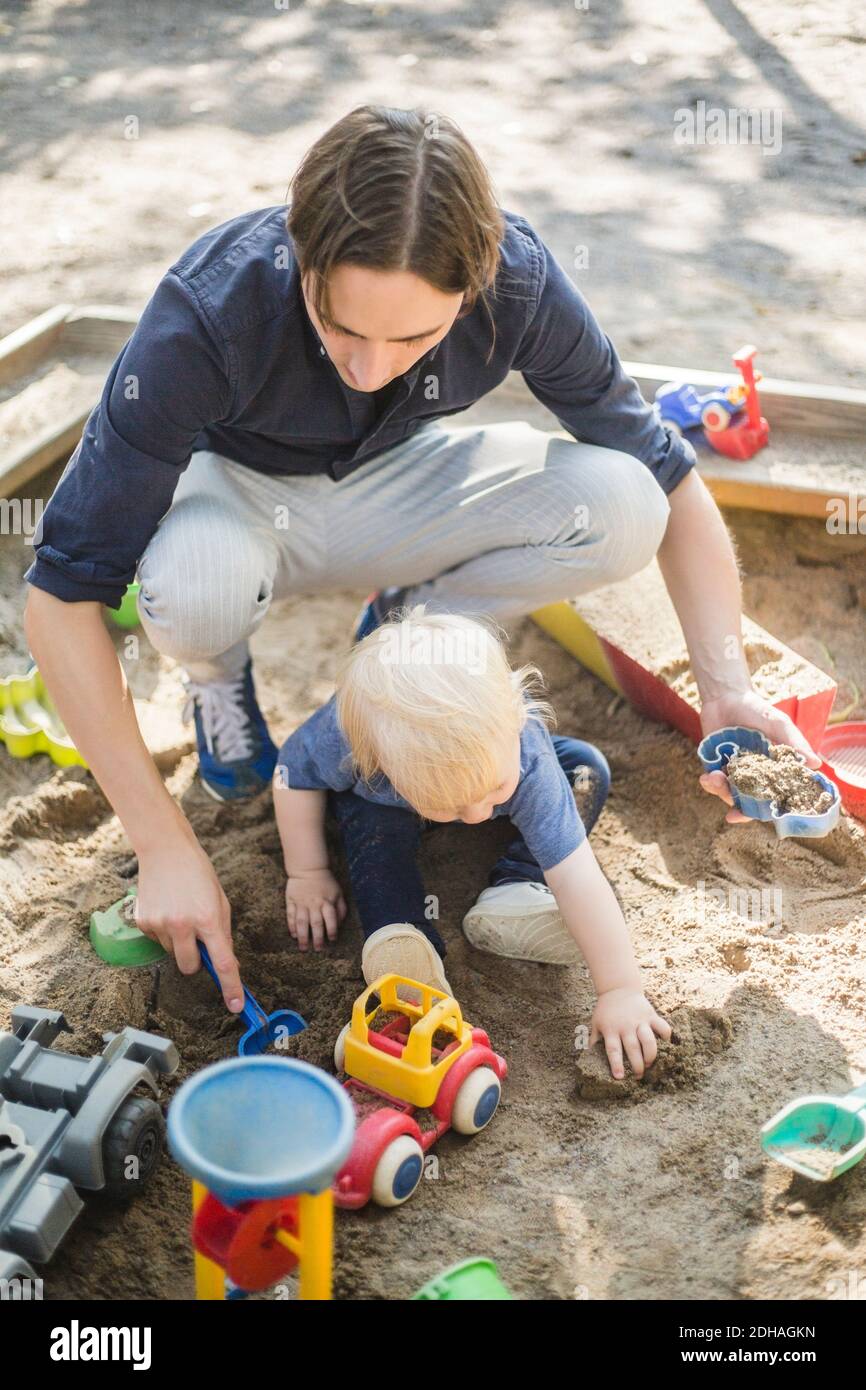 High-Angle-Ansicht von Vater und Sohn spielen mit Spielzeug Auf Sand im Spielplatz im Park Stockfoto