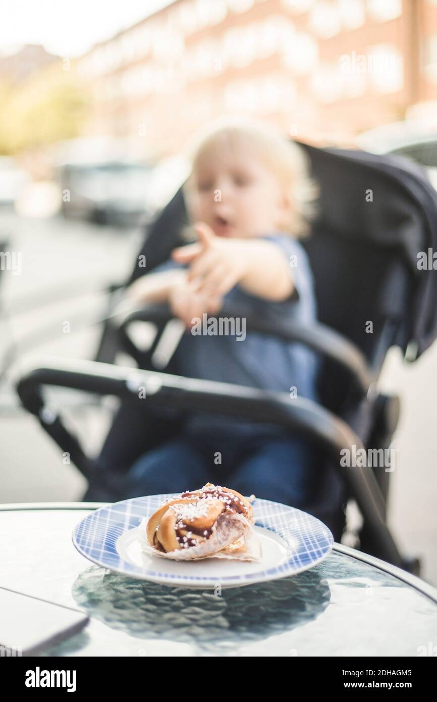 Frisches Gebäck serviert in Teller mit Baby Junge auf Kinderwagen Im Straßencafé Stockfoto