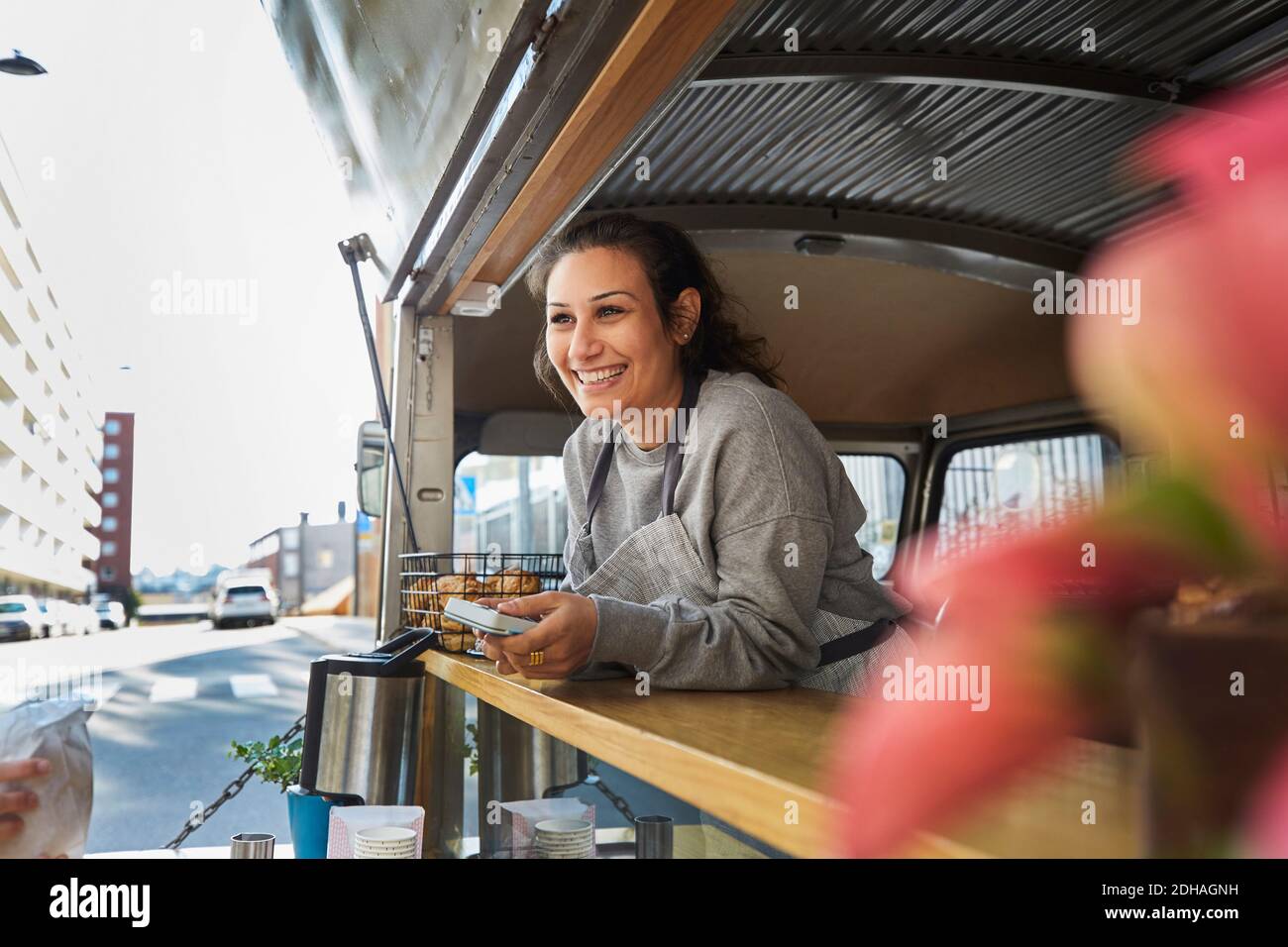 Lächelnde mittlere Erwachsene weibliche Besitzerin am Food Truck in der Stadt Stockfoto