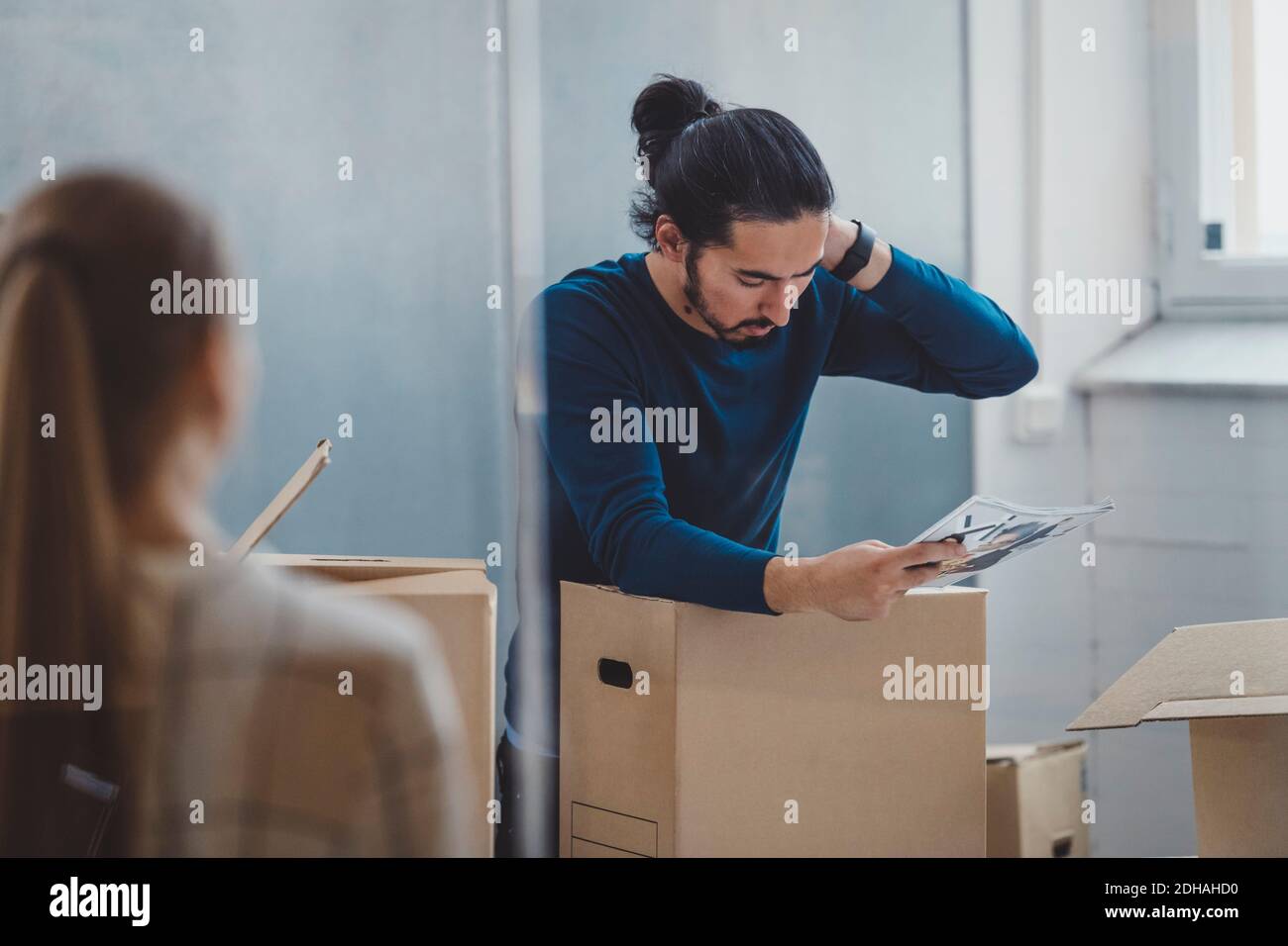 Junger Geschäftsmann liest Buch beim Auspacken Karton in neue Büro Stockfoto