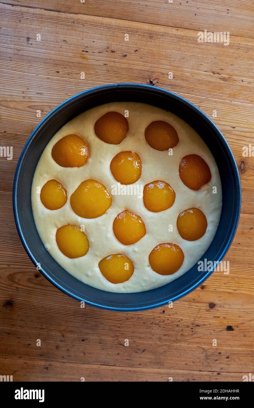 Aprikosen auf rohem Kuchenteig in einem blauen Backen verteilen Schwenken Stockfoto