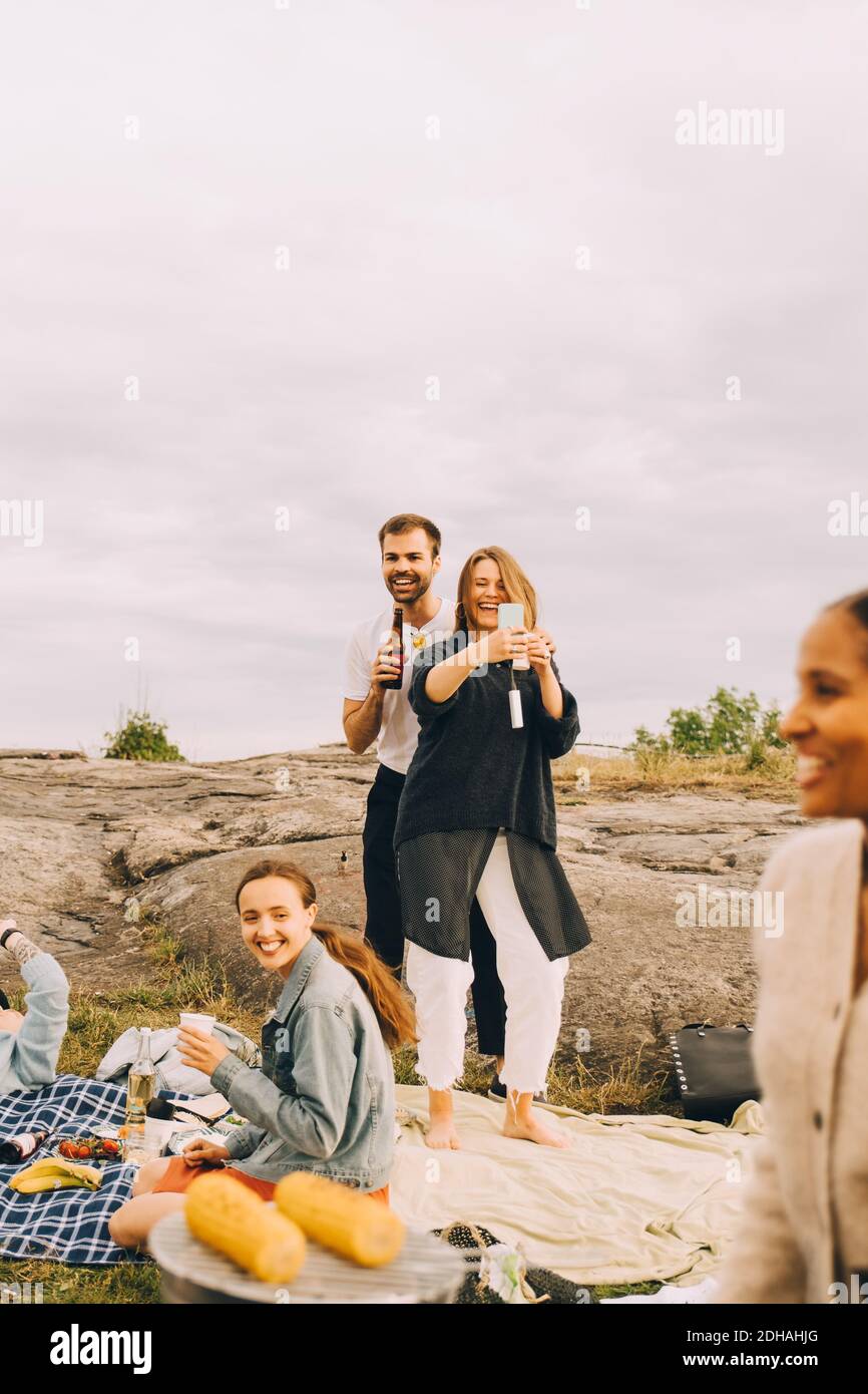 Frau, die Selfie mit einem Freund nimmt, während sie im Picknick genießt Stockfoto