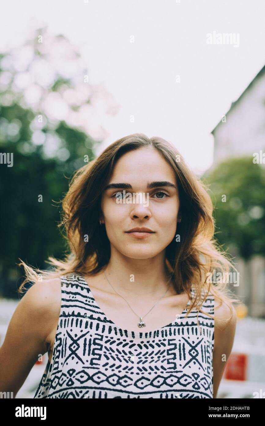 Nahaufnahme Porträt einer jungen Frau mit braunen Haaren gegen den Himmel Stockfoto