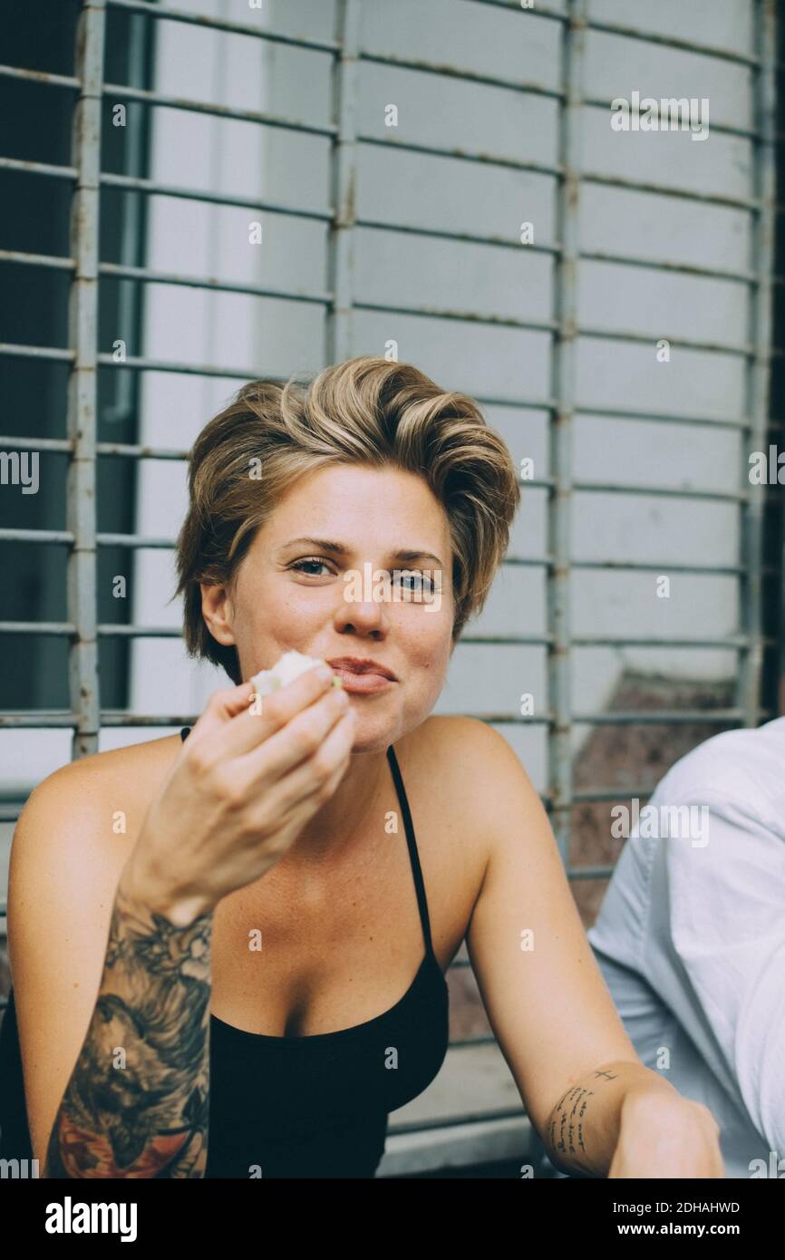 Portrait einer lächelnden Frau mit kurzen Haaren, die Früchte isst Angezeigt Stockfoto