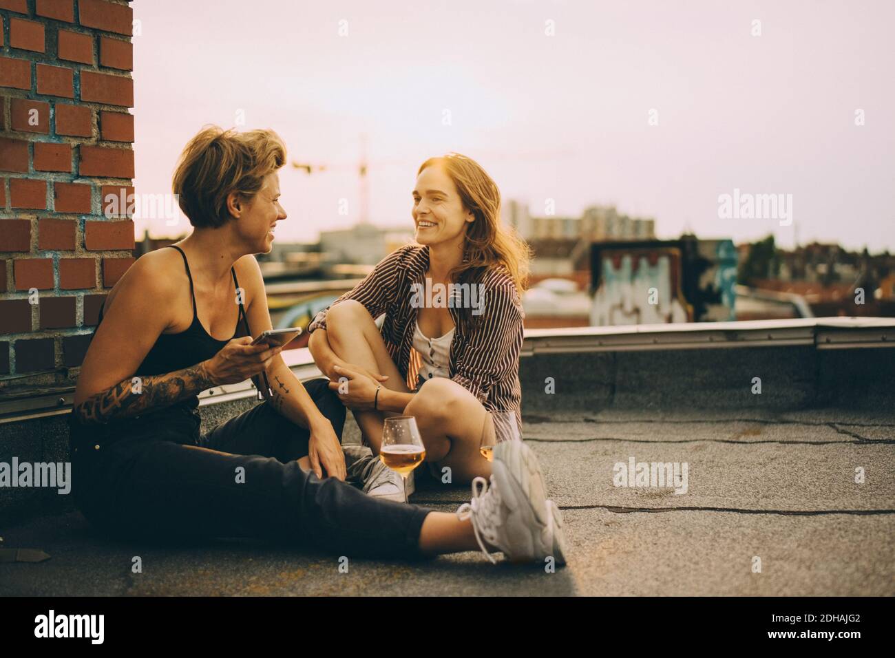 Glückliche Freundinnen reden, während sie auf der Terrasse in der Stadt sitzen Während der Dachparty Stockfoto