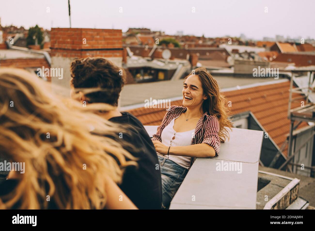 Fröhliche junge Frau genießen Dachparty mit Freunden auf der Terrasse In der Stadt Stockfoto