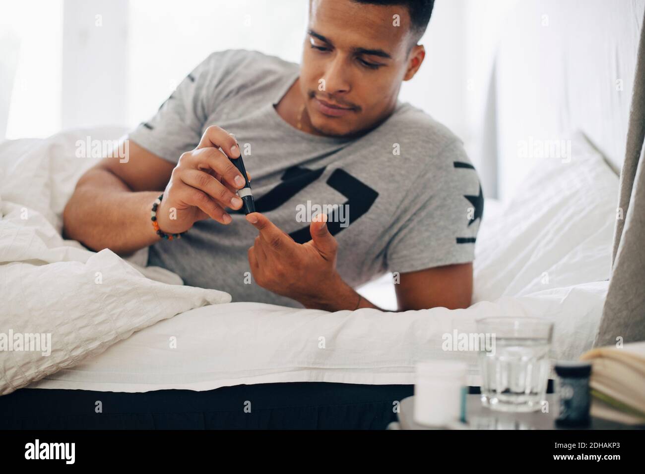 Mann, der zu Hause auf dem Bett liegt und einen medizinischen Test macht Stockfoto