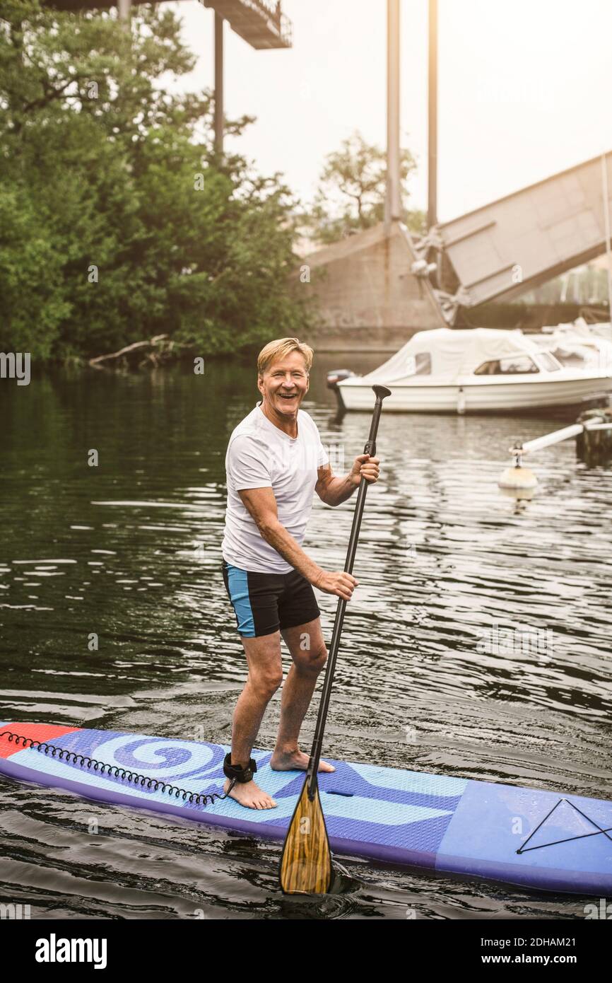 Porträt eines lächelnden Senior Mann Paddleboarding im Meer während SUP Kurs Stockfoto