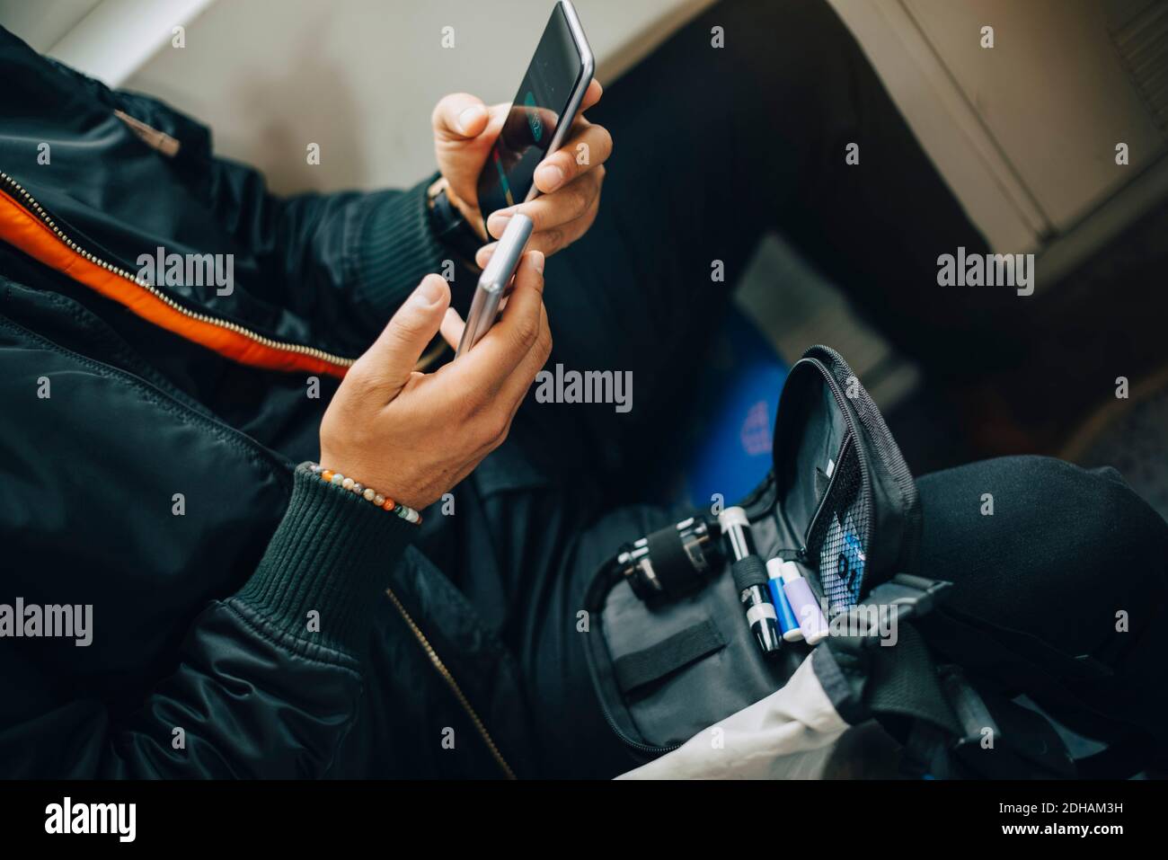 Mann, der den Blutzuckerspiegel mit Glaukome überprüft, während er ein Handy benutzt Telefon im Zug Stockfoto