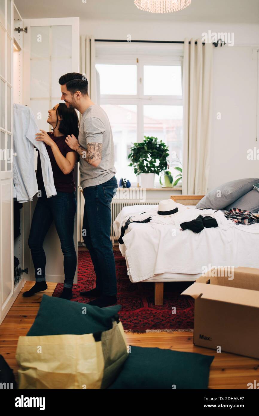 Mann und Frau arrangieren Kleider zusammen im Schrank bei neu Zu Hause Stockfoto