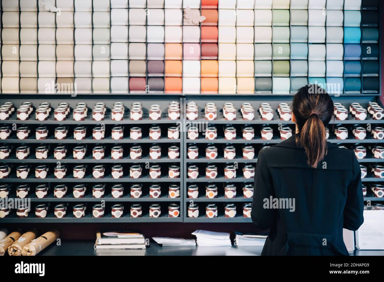 Rückansicht der Frau Auswahl Tapeten und Farben angezeigt Verkauf im Geschäft Stockfoto