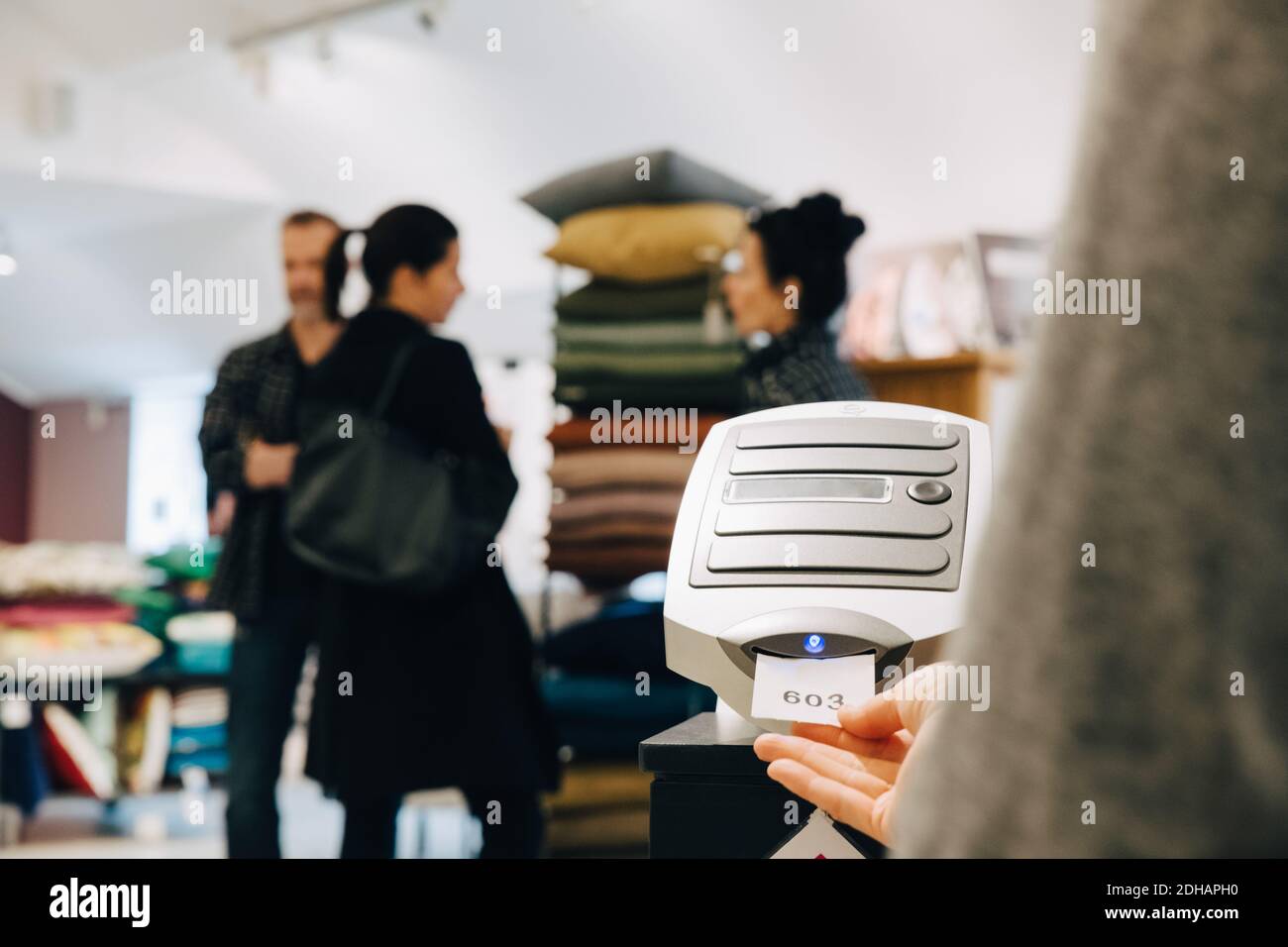 Frau hält Papier von der Maschine, während die Leute im Hintergrund diskutieren Stockfoto