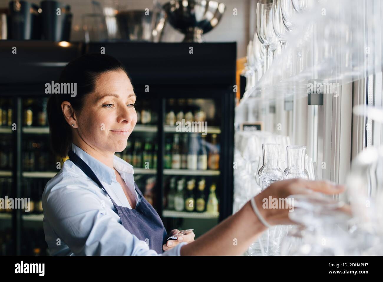 Lächelnde Frau, die im Restaurant Weingläser arrangierte Stockfoto
