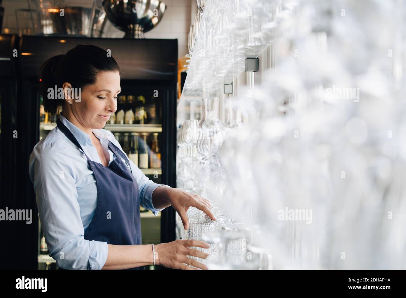 Lächelnde Frau, die im Restaurant Weingläser arrangierte Stockfoto