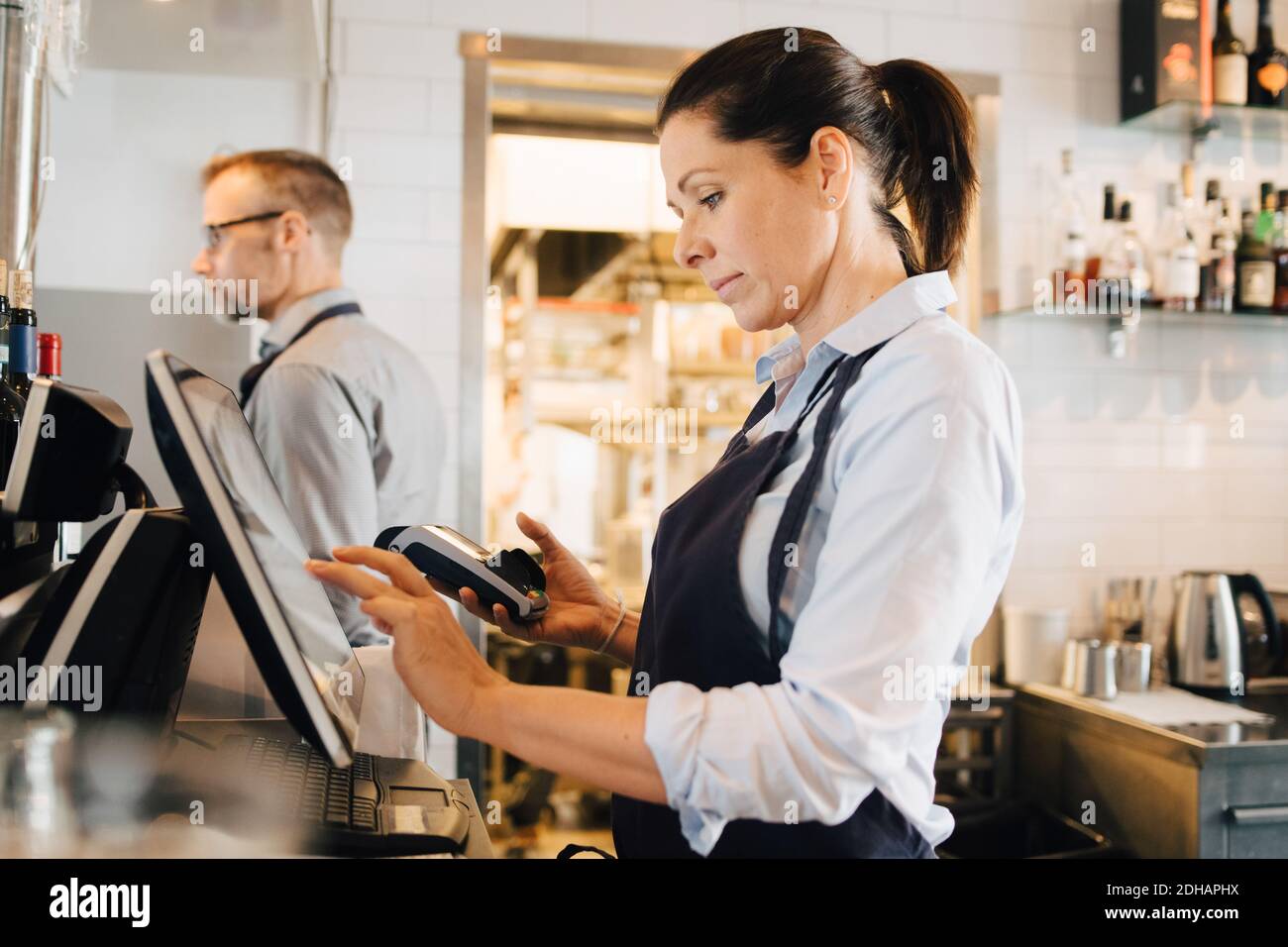 Besitzer mit Computer, während die Kreditkarte Leser im Restaurant Stockfoto