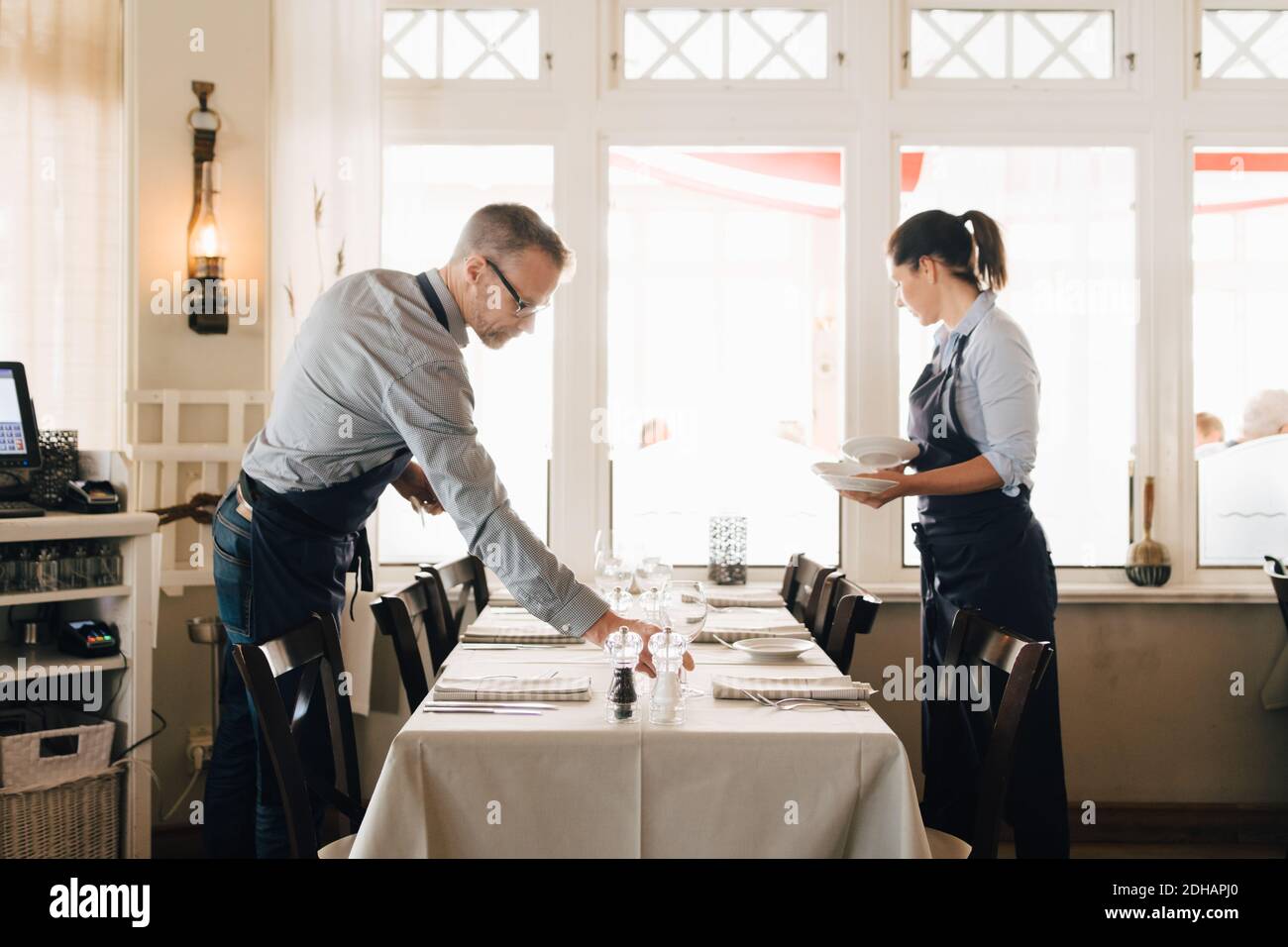 Männliche und weibliche Mitarbeiter arrangieren Tisch im Restaurant Stockfoto