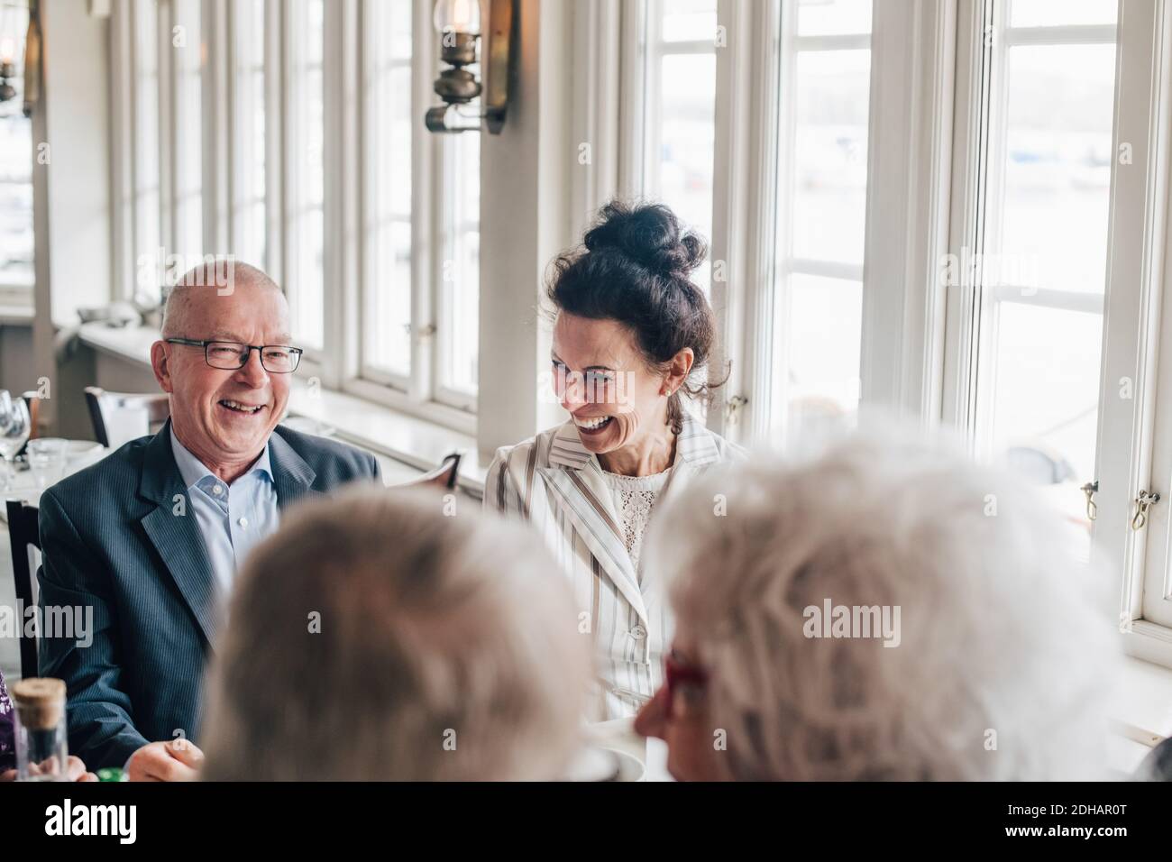 Ältere Freunde lächeln, während sie im Restaurant sitzen Stockfoto