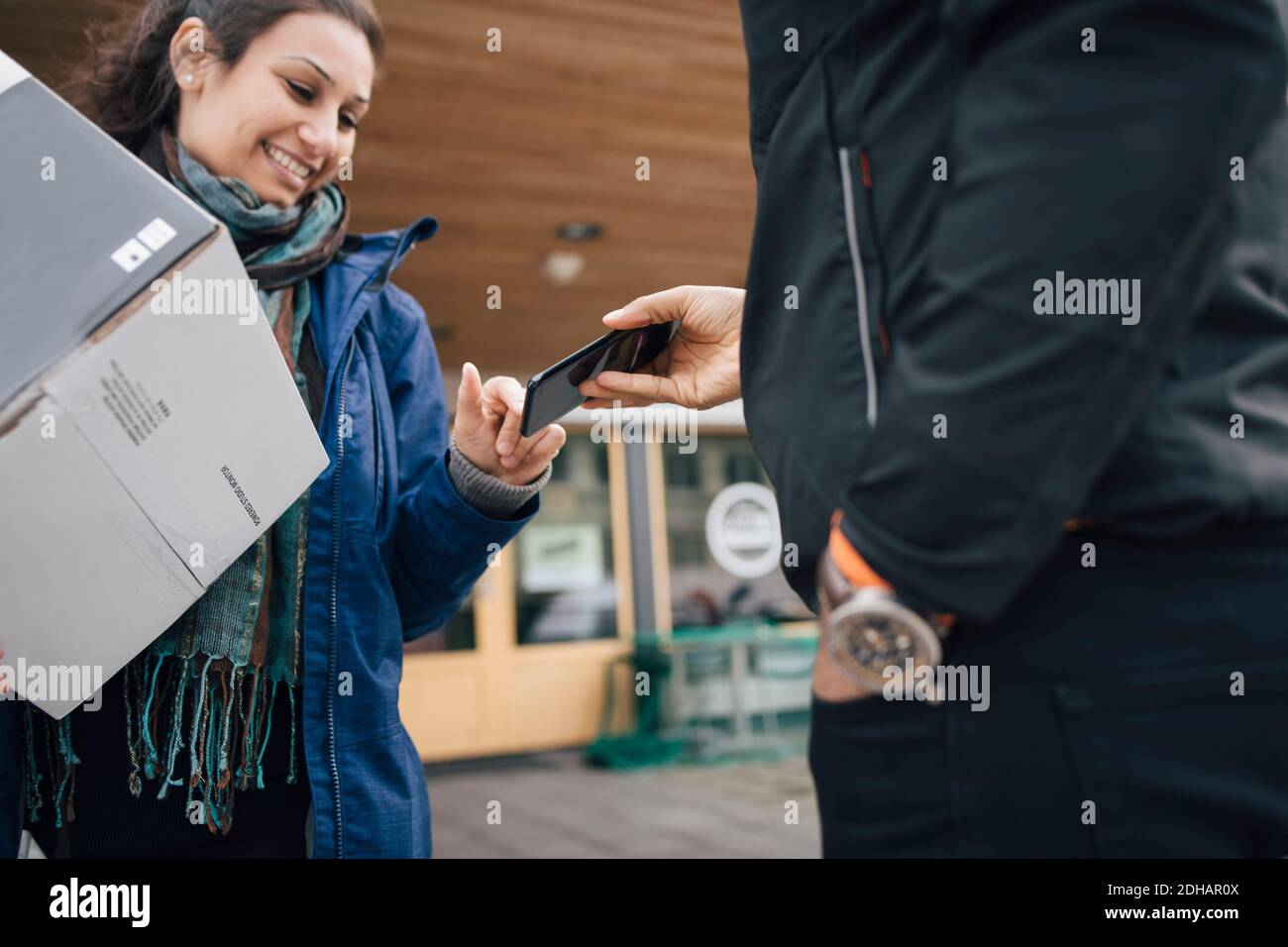 Lächelnde Frau mit Smartphone für ihre Lieferung zu unterzeichnen Vom Messenger Stockfoto