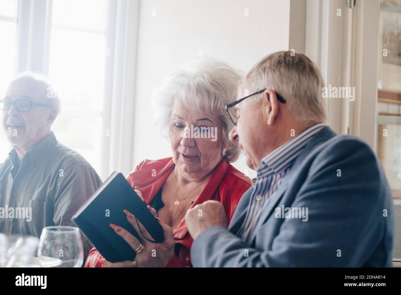 Ältere Frau, die mit einem Freund spricht, während sie Buch hält Restaurant Stockfoto