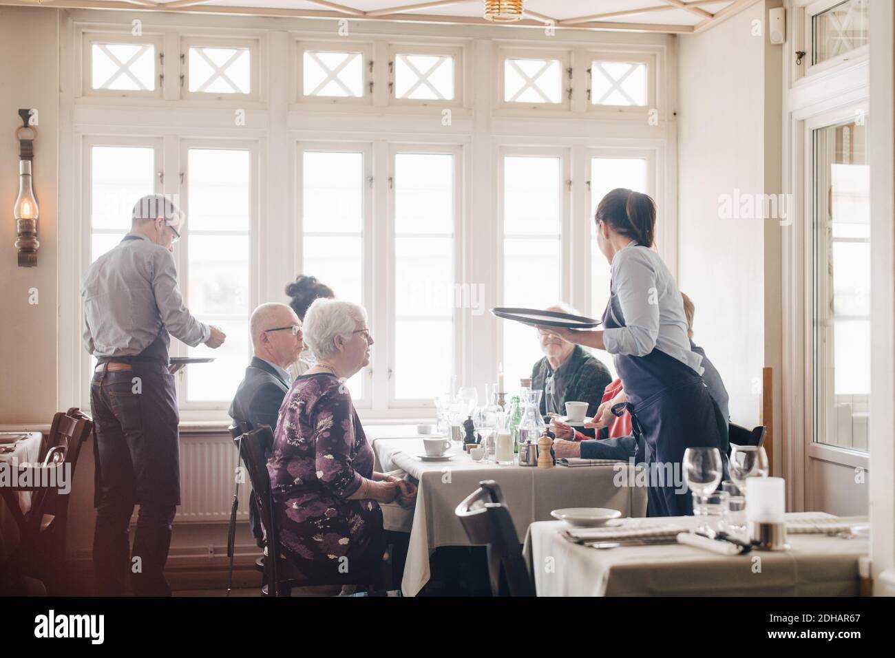 Die Besitzer servieren Kaffee für männliche und weibliche Freunde, die an ihnen sitzen Restauranttisch Stockfoto