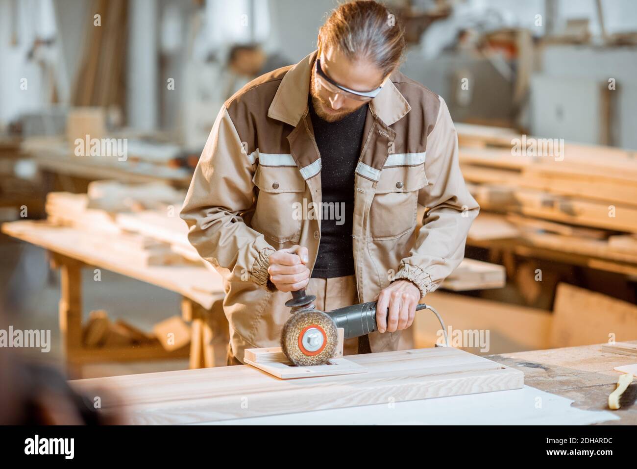 Schöner Zimmermann im einheitlichen Bürsten Holz mit Handmaschine an Die Tischlerei Herstellung Stockfoto