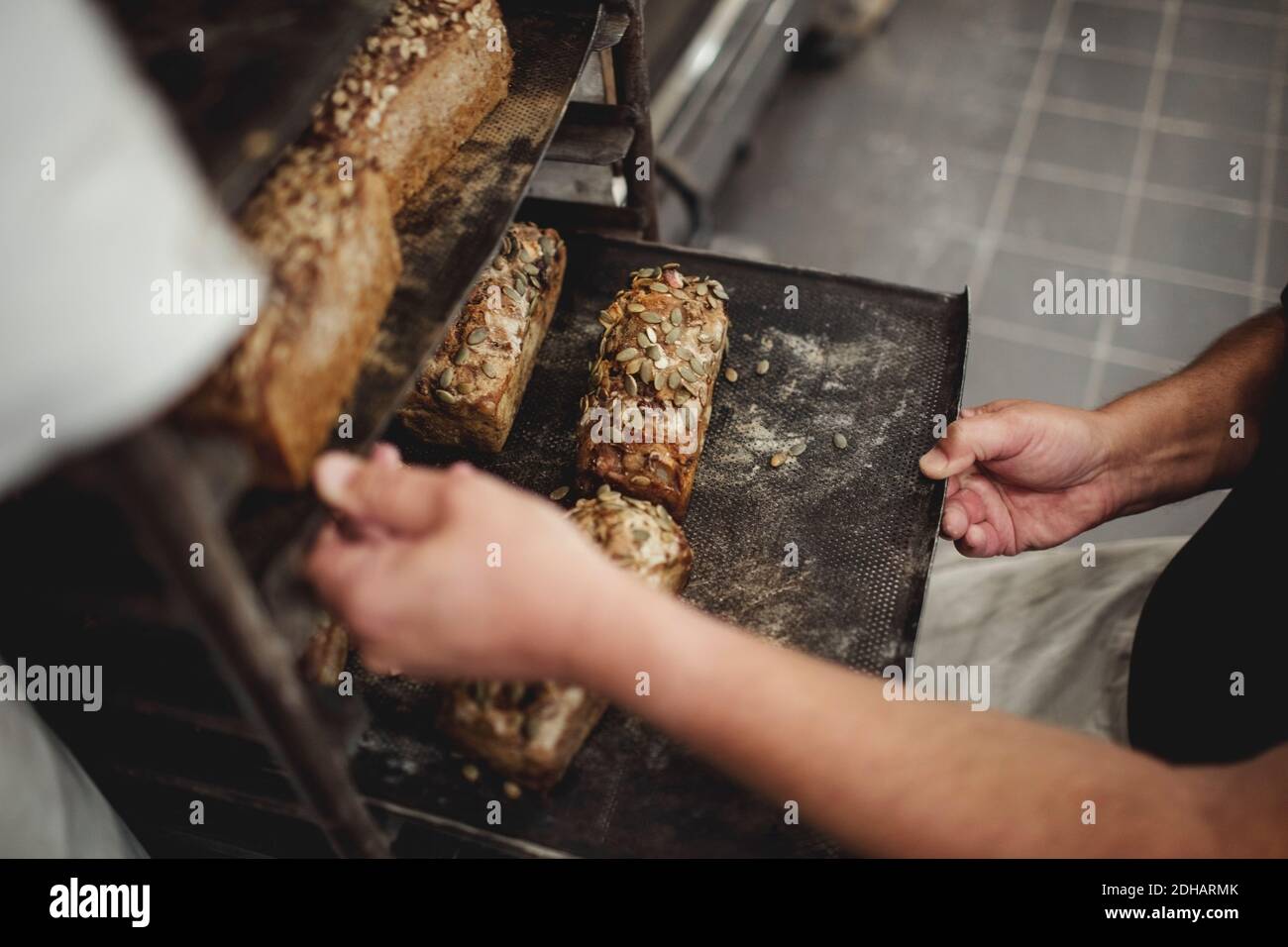 In der Mitte des Bäckers halten wir frisch gebackene Brote auf dem Tablett Kühlregal in der Bäckerei Stockfoto