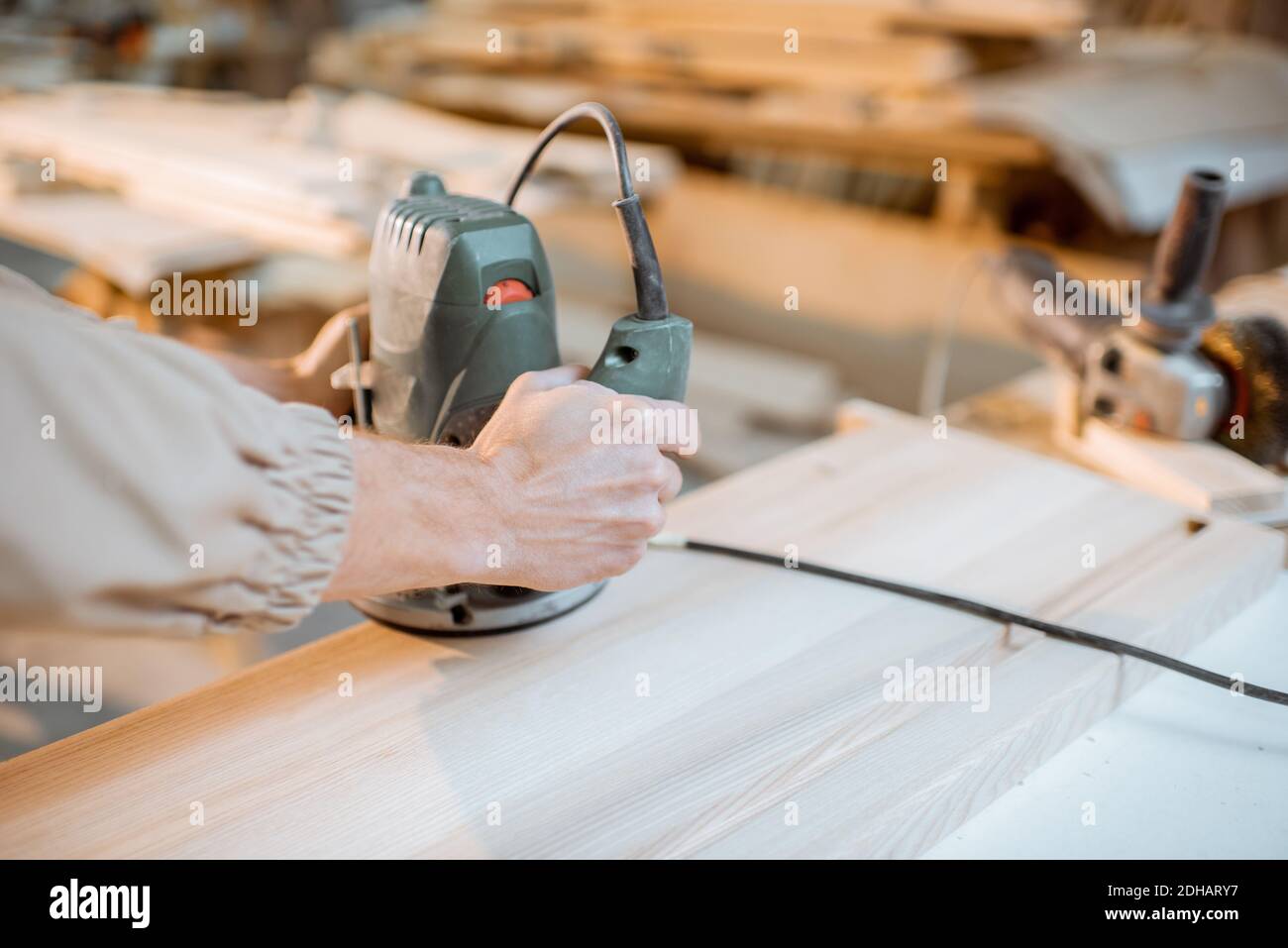 Werker fast Holzbalken mit einer Handmaschine an der Schreinerei, Nahaufnahme Stockfoto