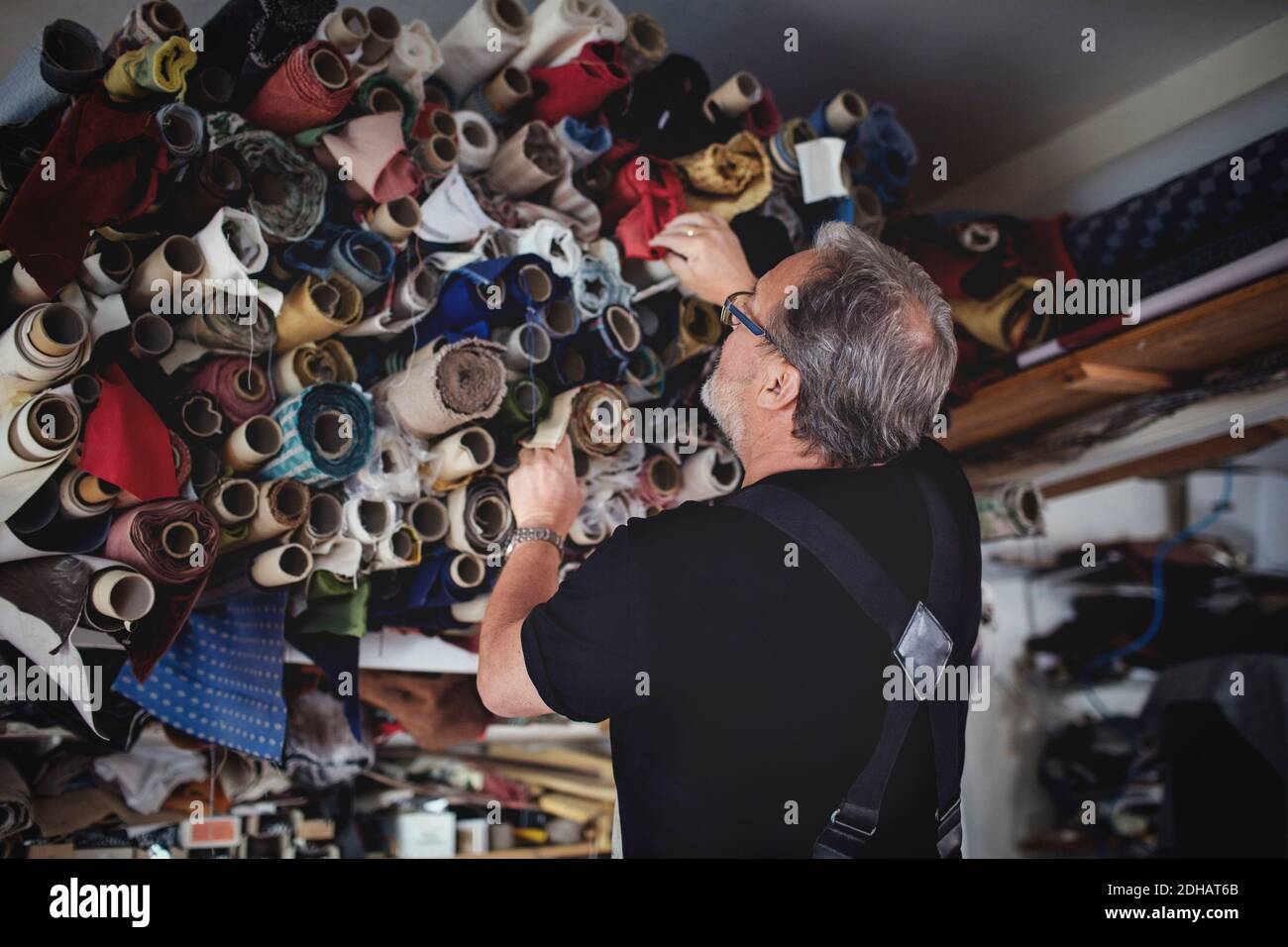 Low-Winkel-Ansicht von älteren männlichen Besitzer Blick auf gerollt Stoffe in der Werkstatt Stockfoto